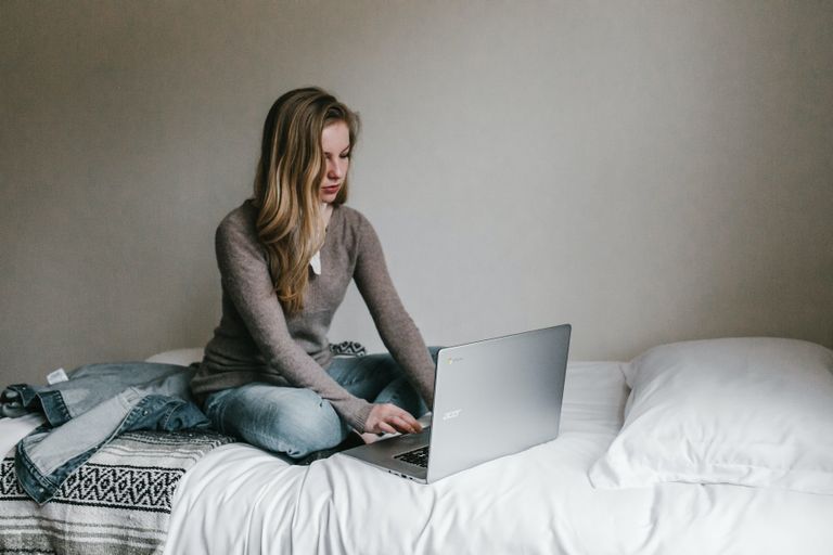 Une femme utilise son ordinateur portable alors qu'elle est assise dans son lit. | Source : Unsplash