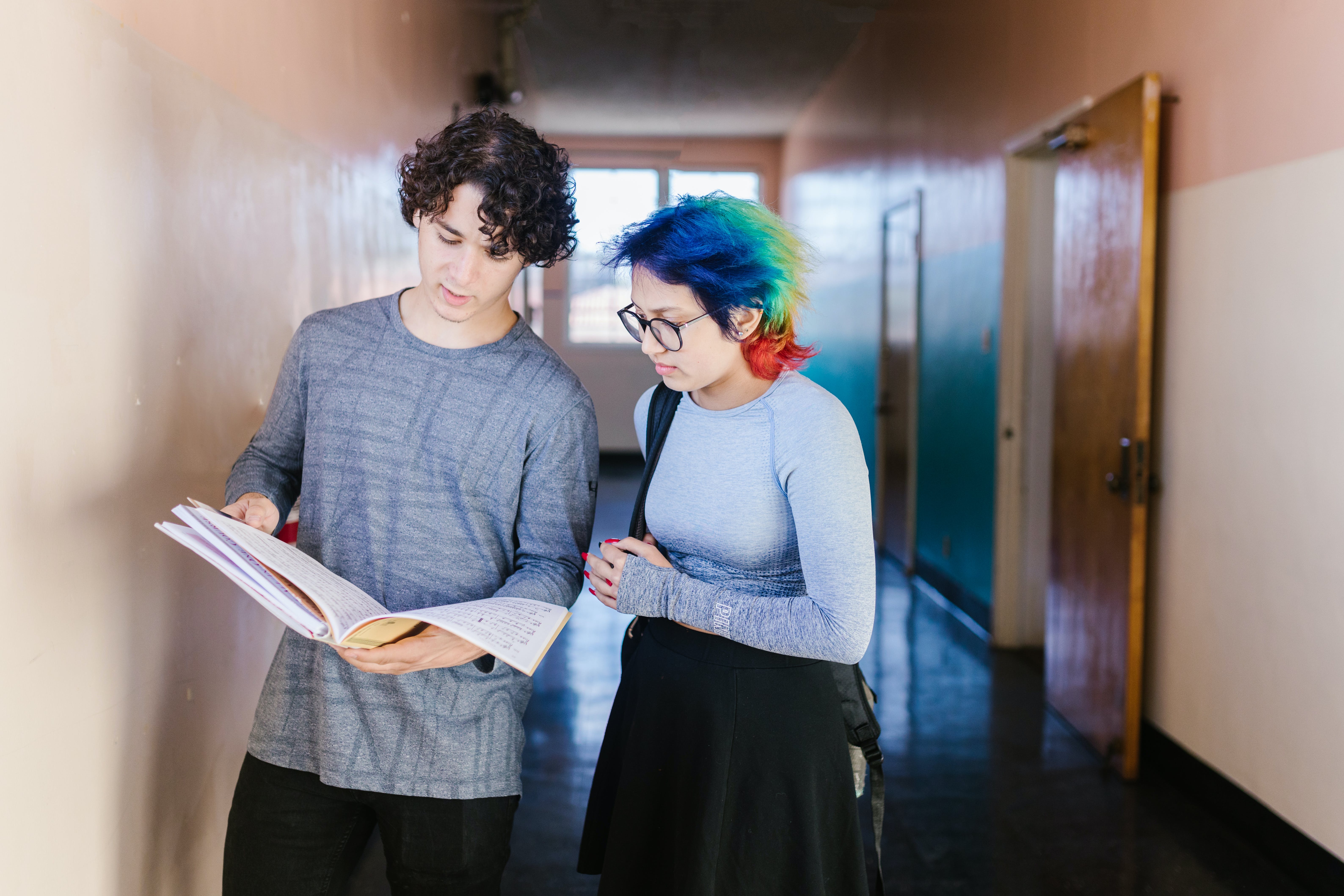 Des adolescents debout avec un livre à l'école | Source : Pexels