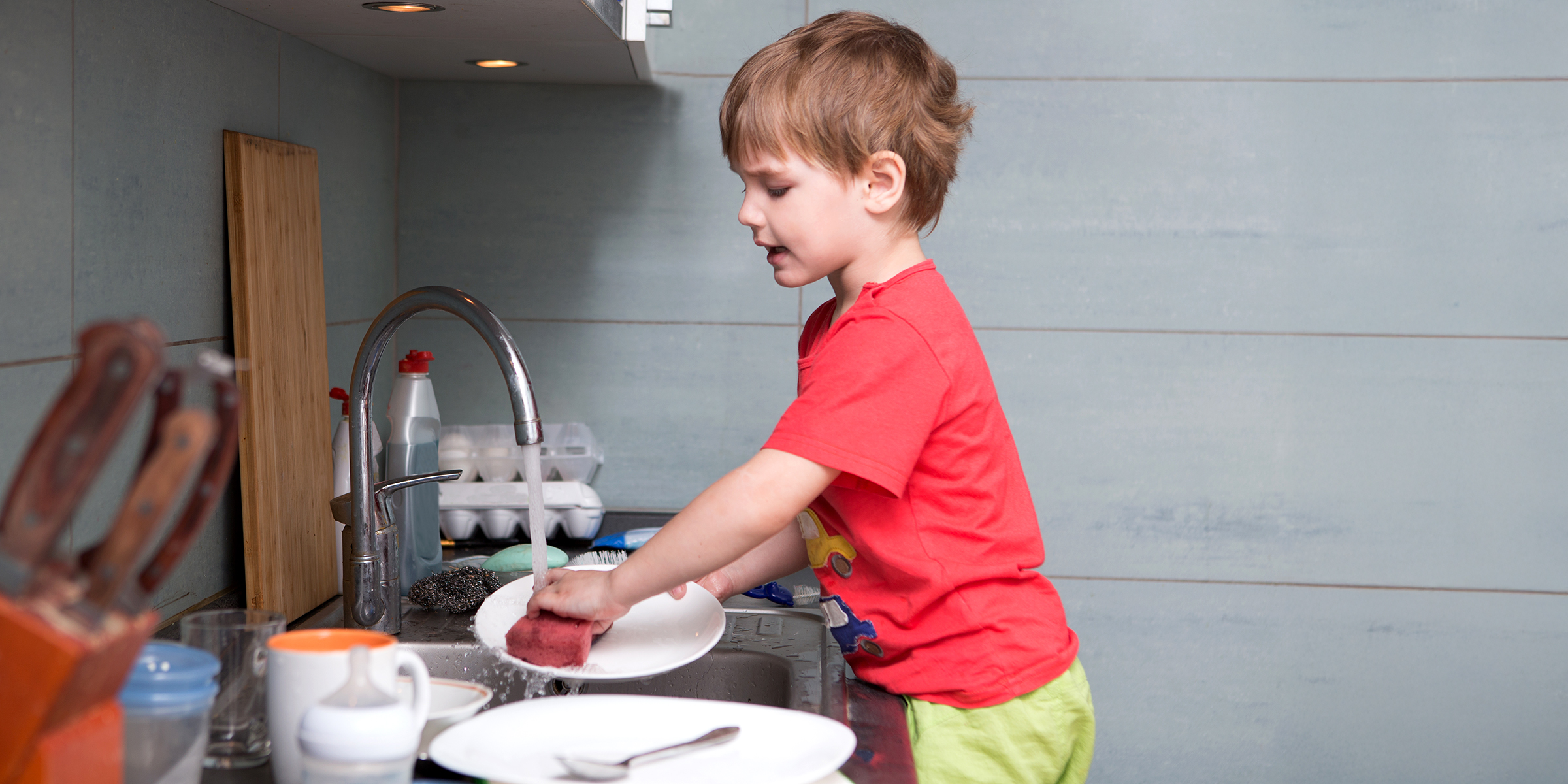 Un garçon qui fait la vaisselle | Source : Shutterstock