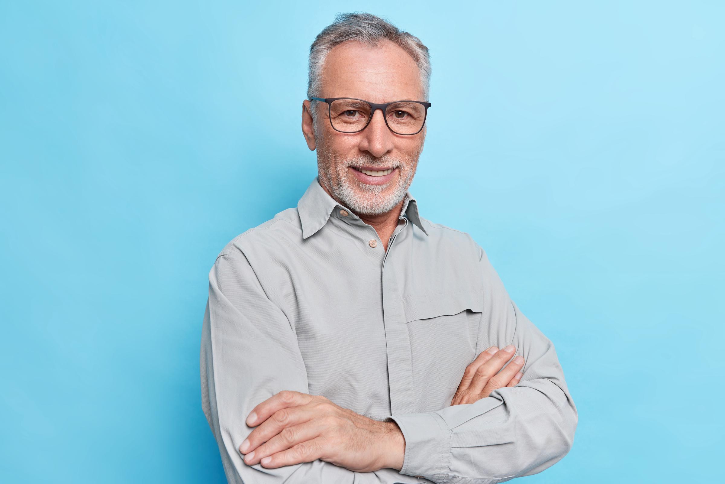 Un homme souriant d'âge moyen avec les bras croisés | Source : Freepik