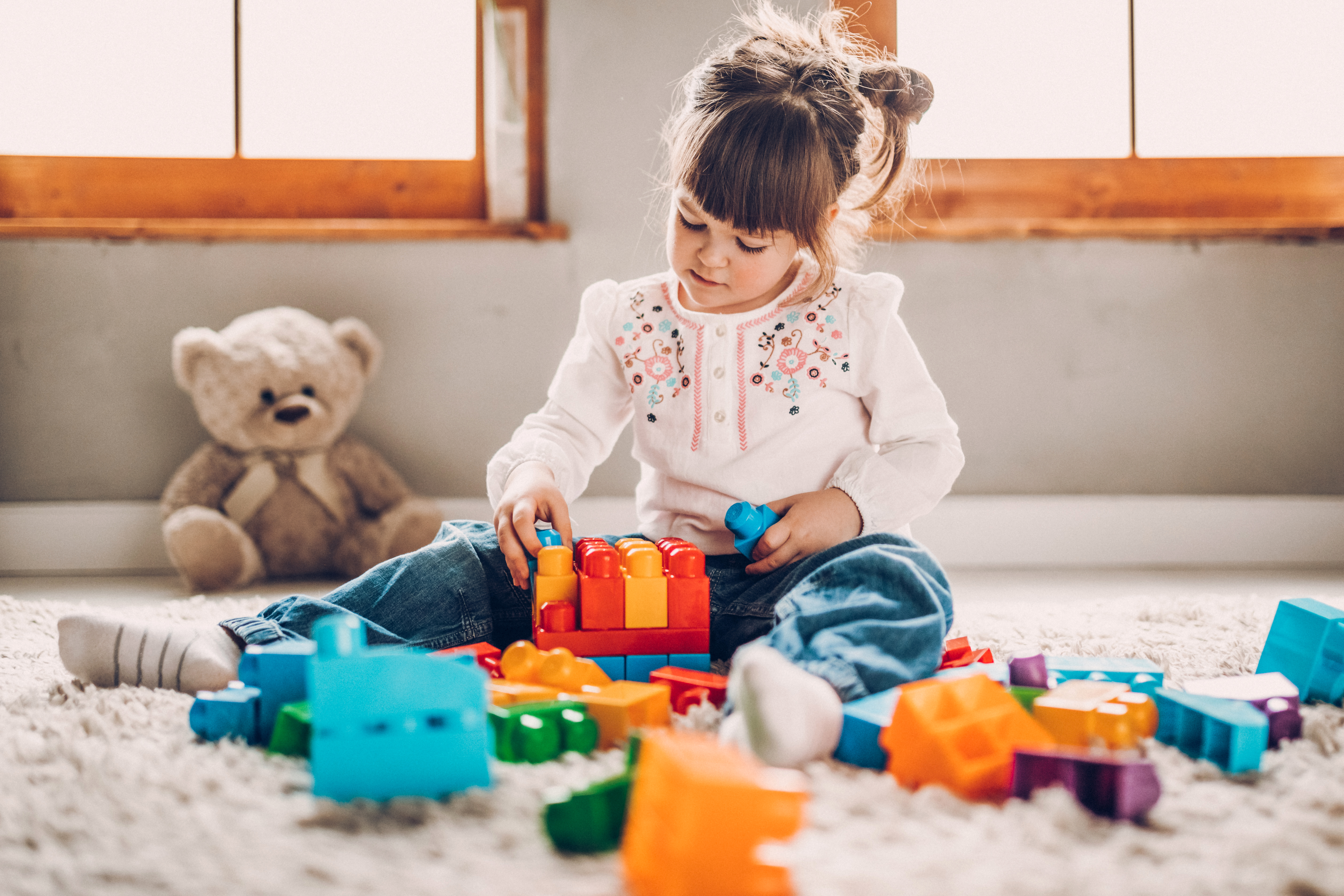 Doux enfant jouant avec des blocs en plastique | Source : Getty Images