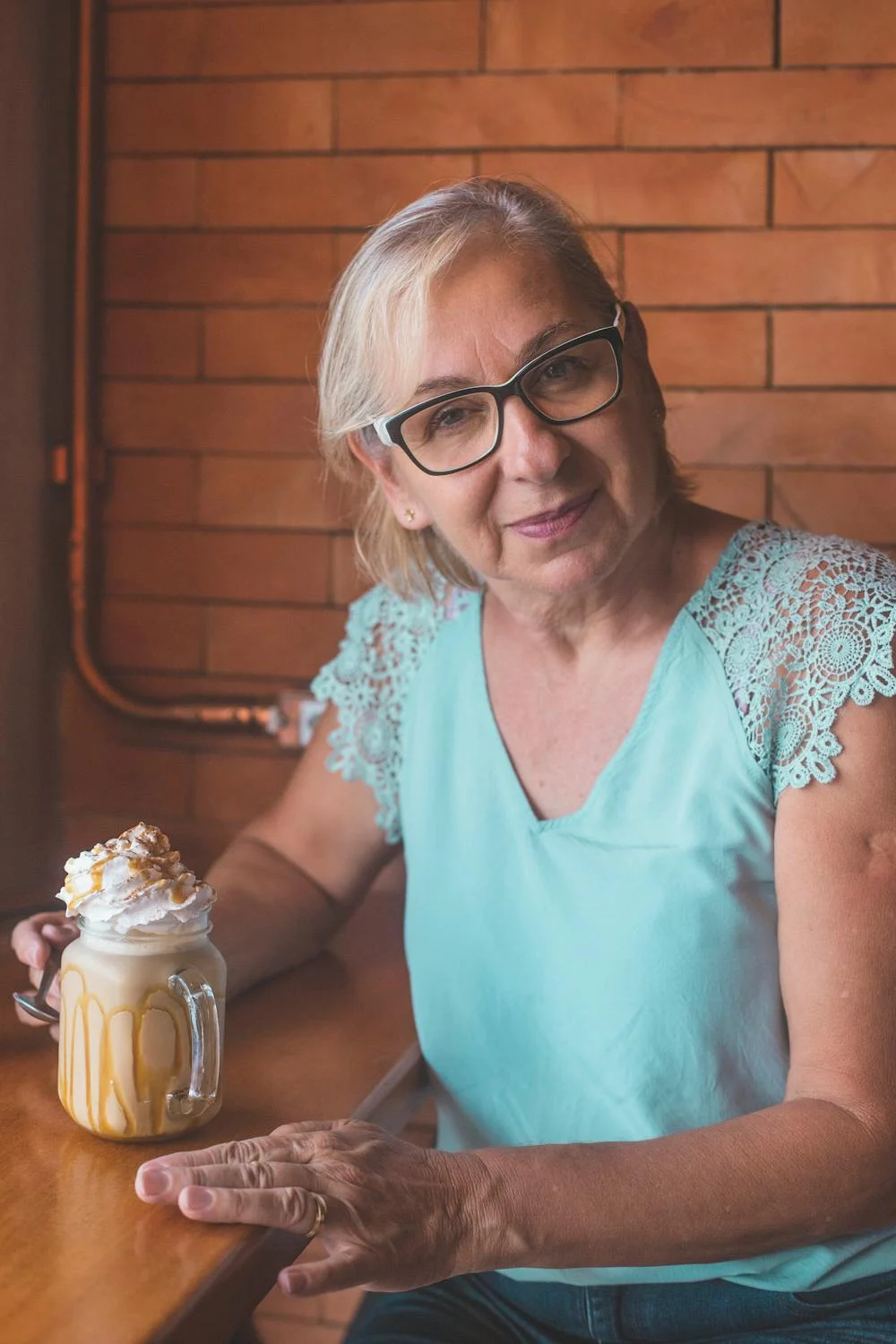 Une femme souriante qui boit du café ⏐ Source : Pexels