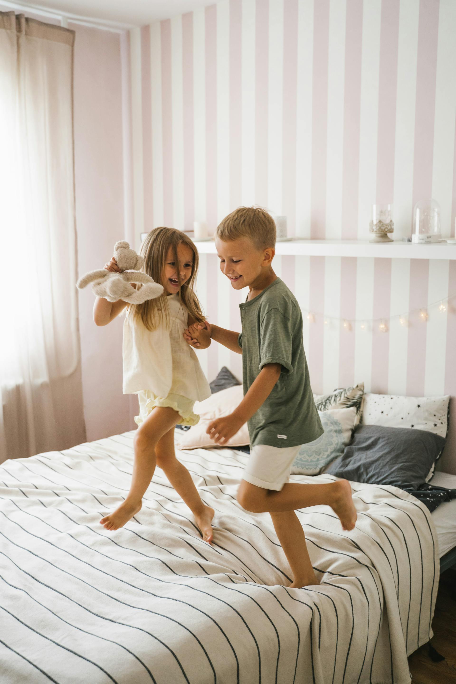 Un garçon et une fille heureux qui dansent sur le lit | Source : Pexels