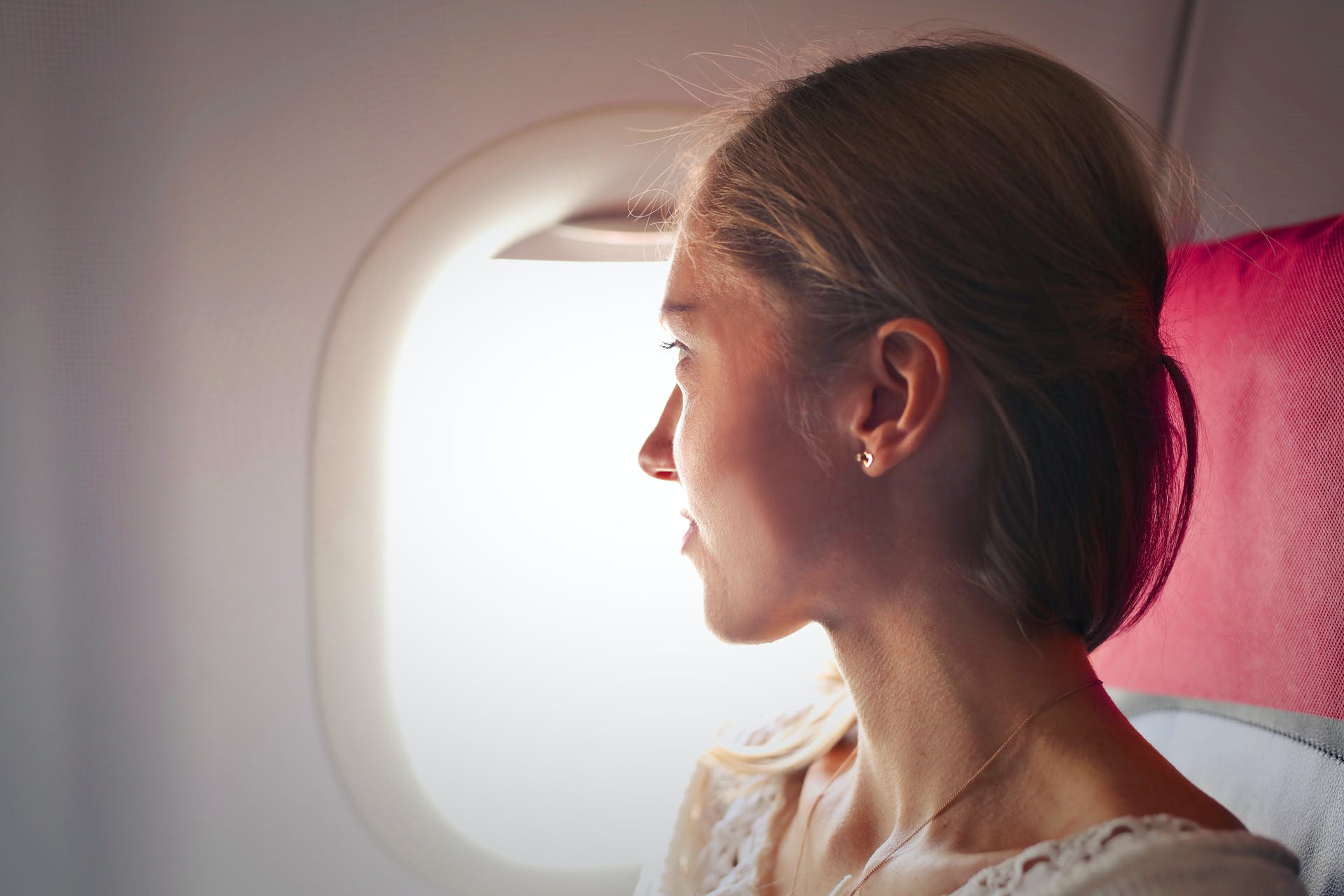 Mujer mirando por la ventanilla de un avión | Fuente: Pexels