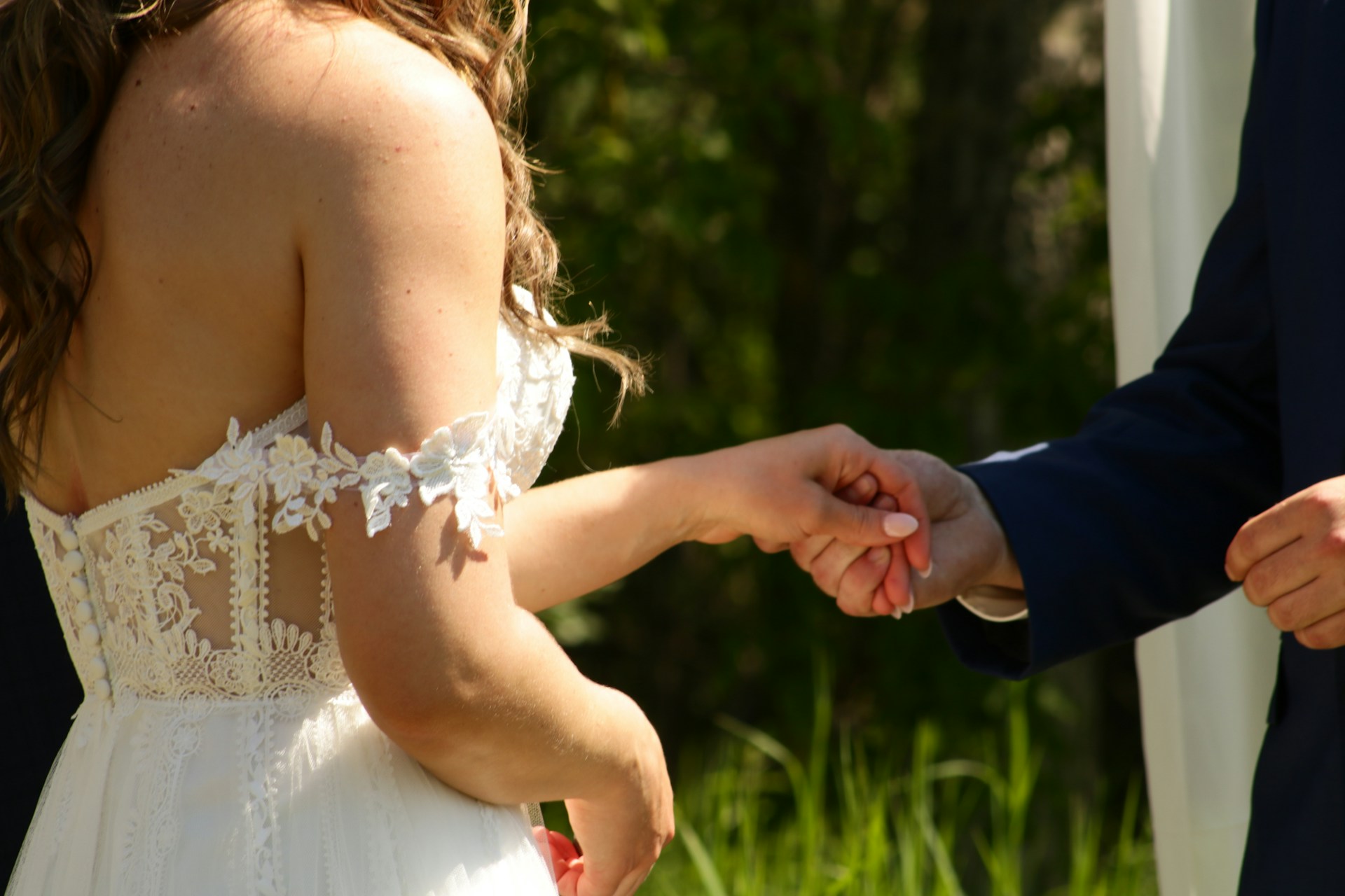 Photo recadrée d'un marié tenant la main de la mariée | Source : Unsplash