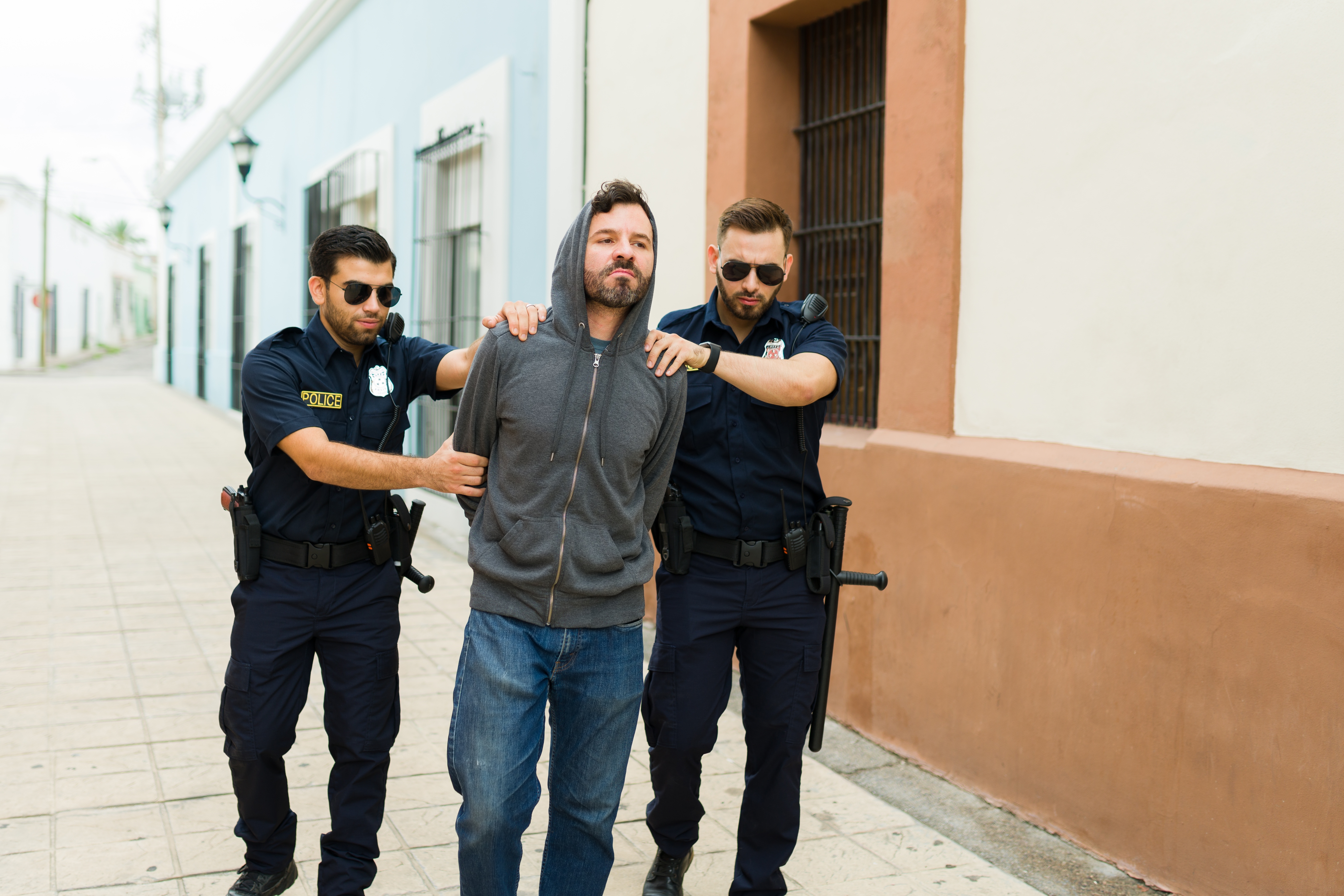 Criminoso violento com capuz sendo preso pela polícia | Fonte: Shutterstock.com