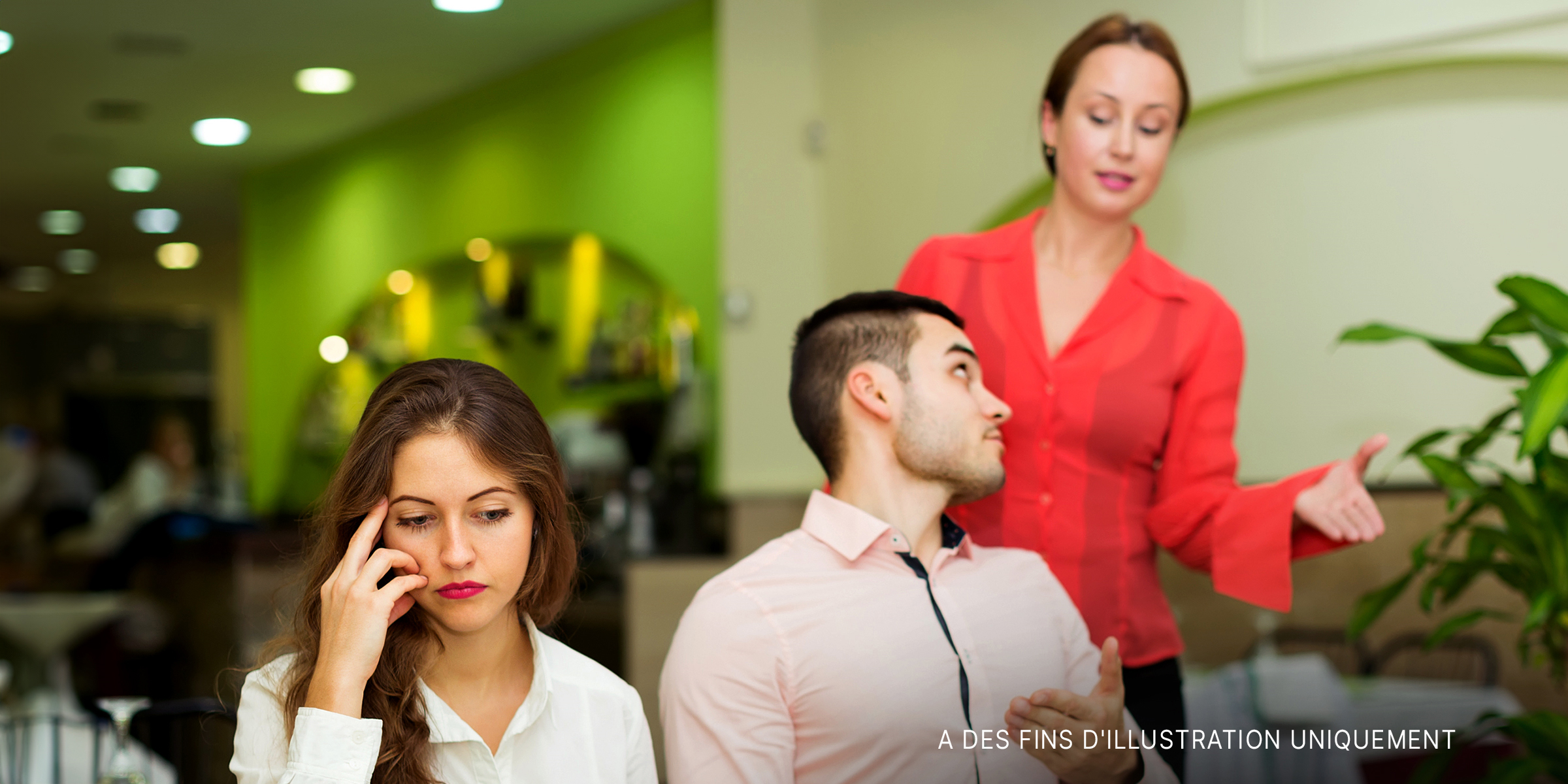 Une femme embarrassée dans un restaurant où son partenaire parle à la serveuse | Source : Shutterstock