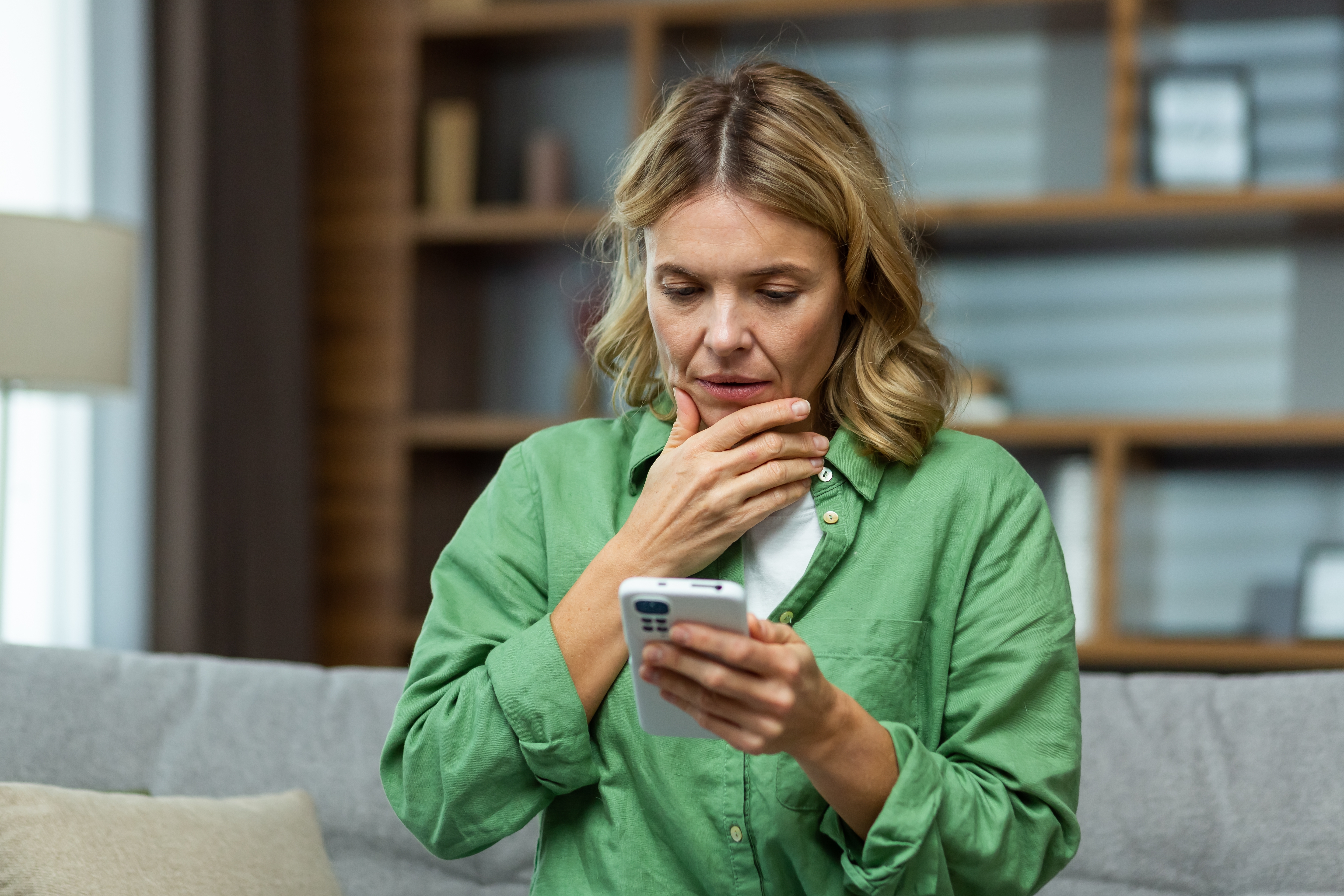 Une femme d'âge moyen semble préoccupée tout en tenant son téléphone | Source : Shutterstock