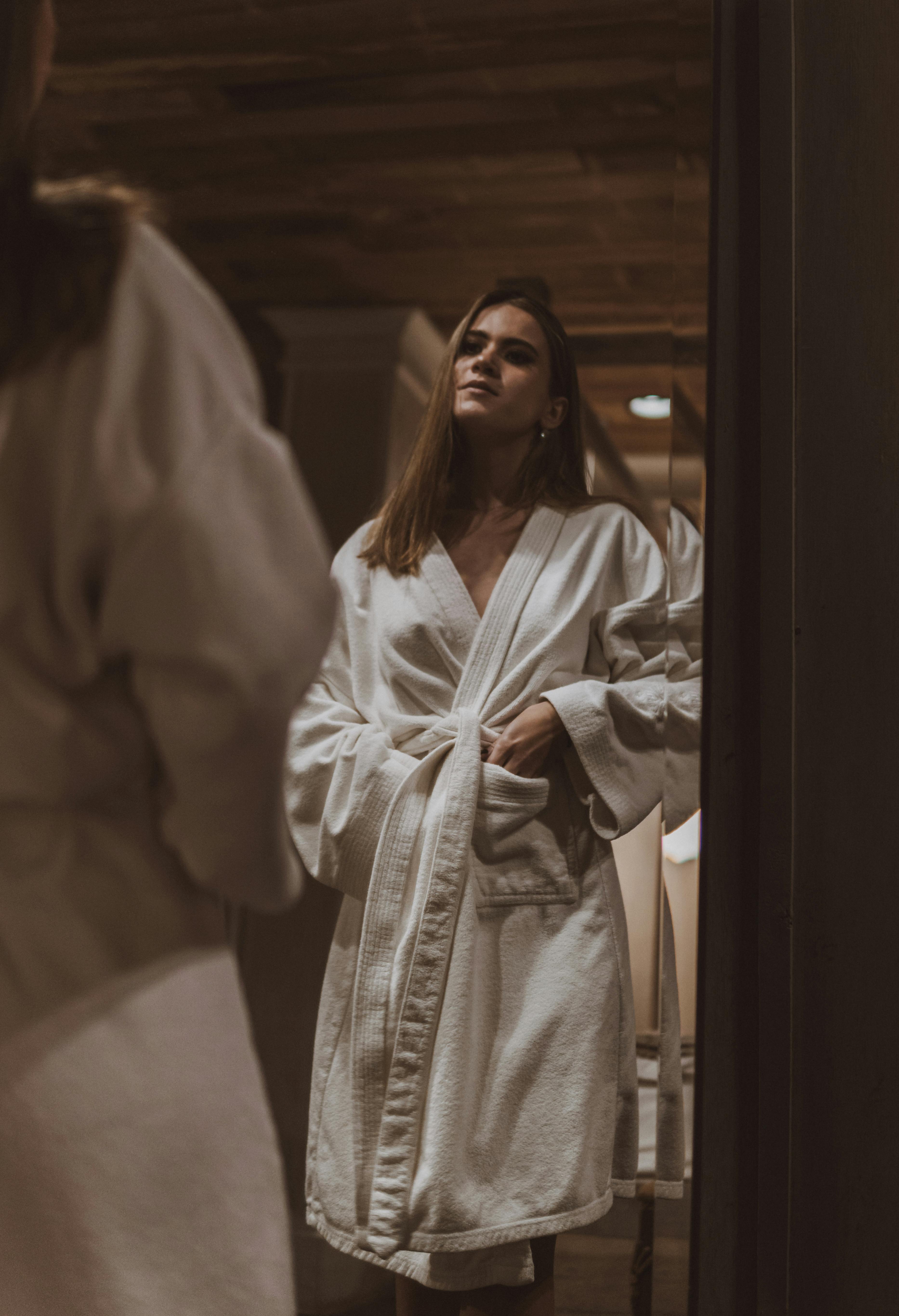 Une femme en peignoir qui se regarde dans le miroir | Source : Pexels