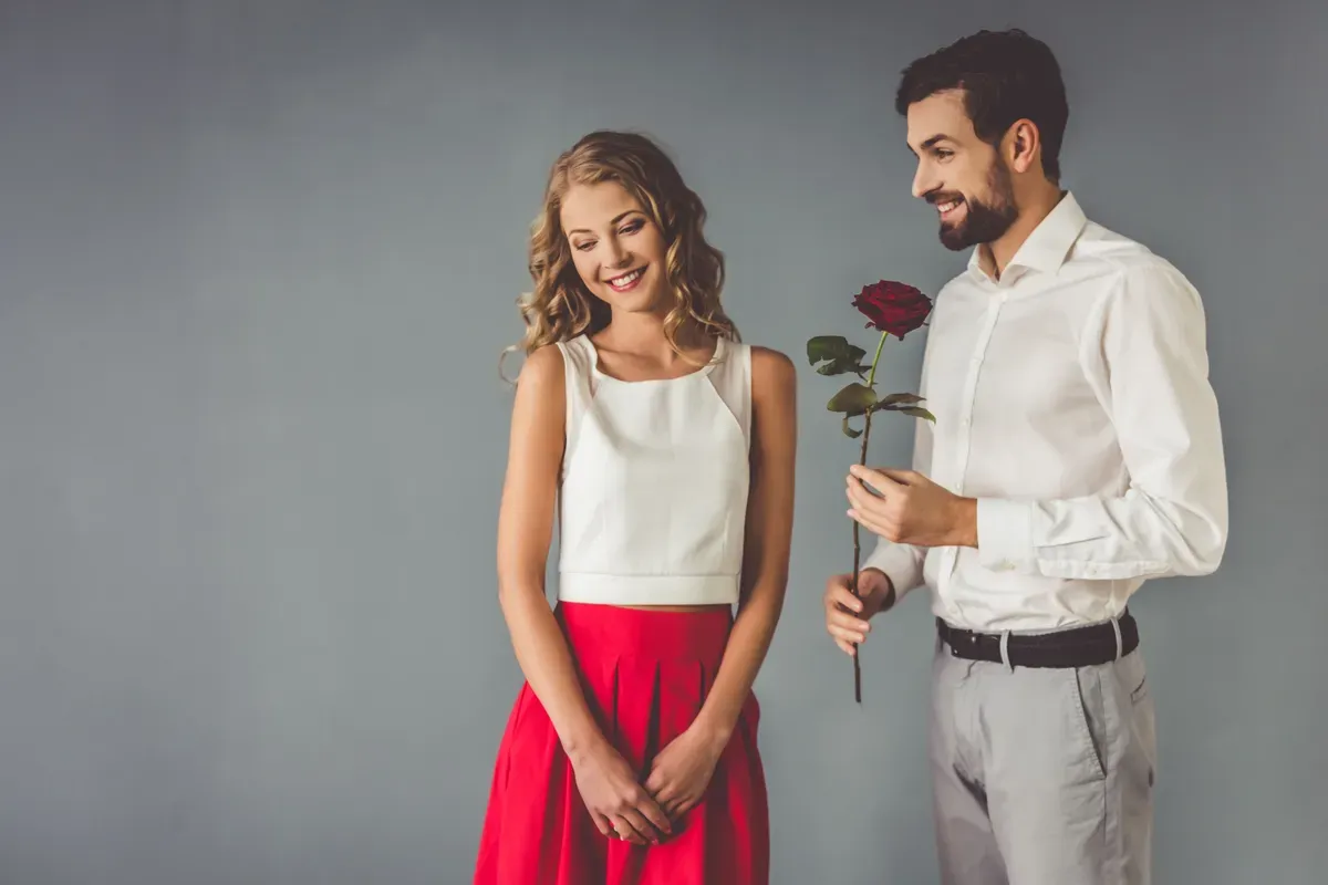 Un homme offre une rose rouge à une femme. | Photo : Shutterstock