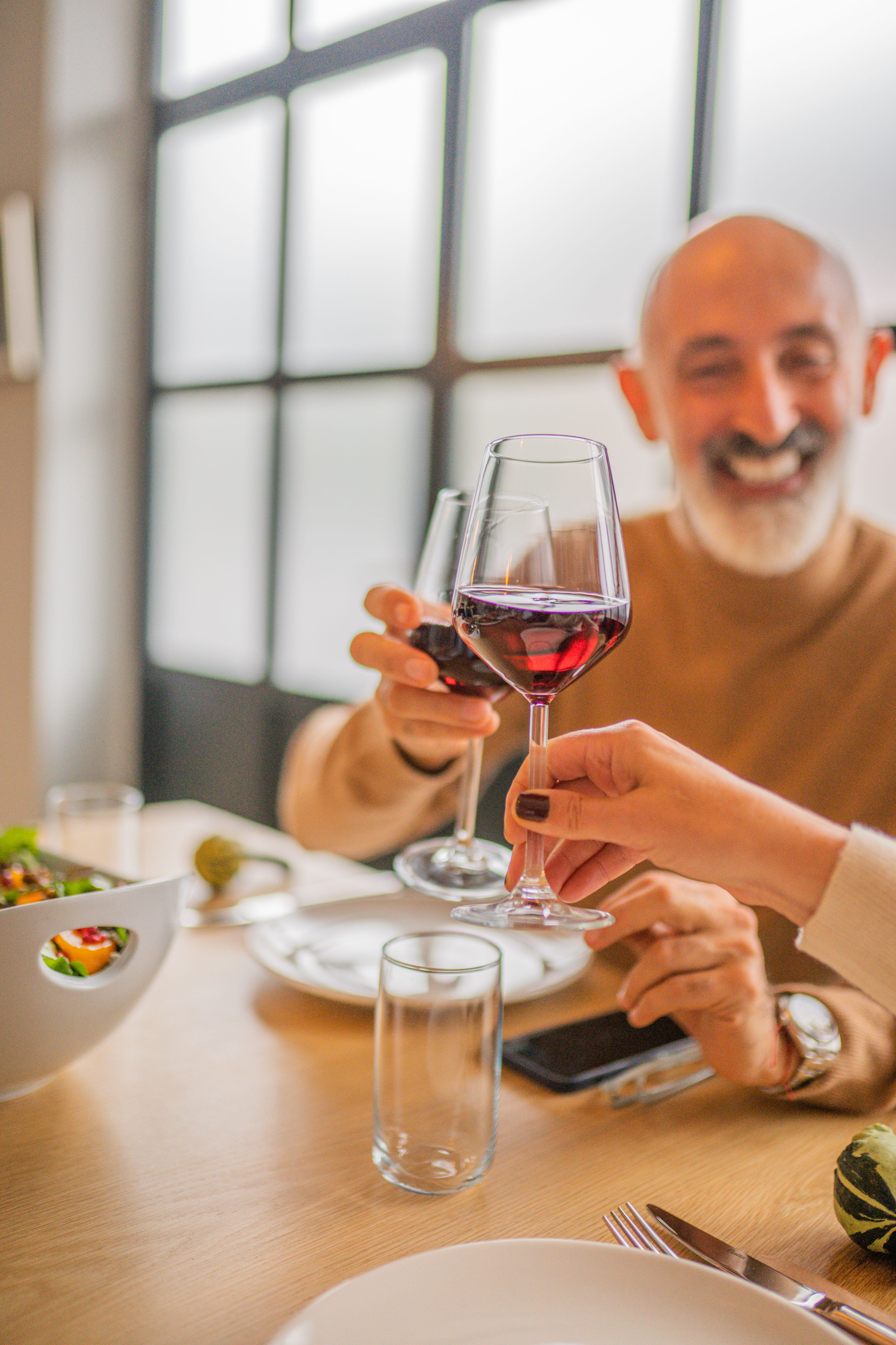 Homme heureux portant un toast en tenant un verre de vin rouge | Source : Pexels