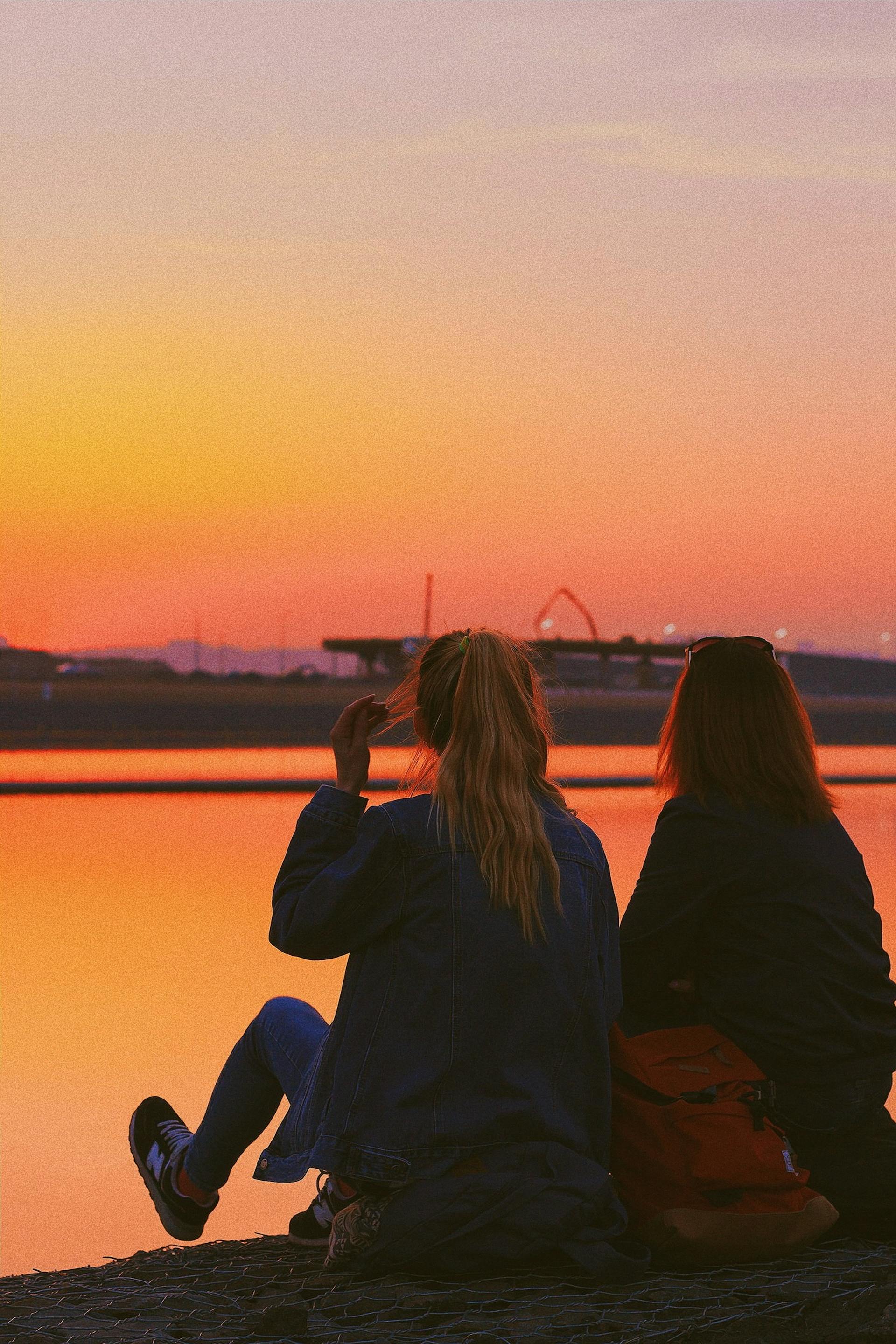 Deux adolescentes assises au bord d'un lac | Source : Pexels