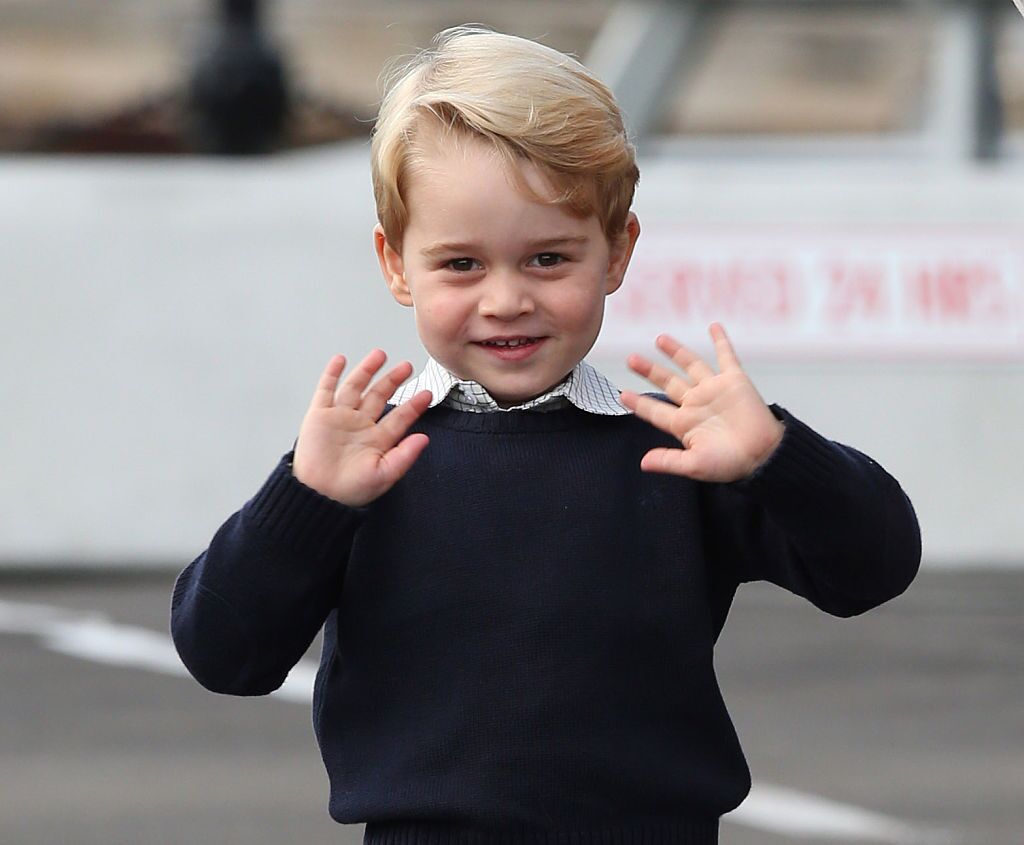 Prince George fait signe à deux mains en souriant. | Source : Getty Images