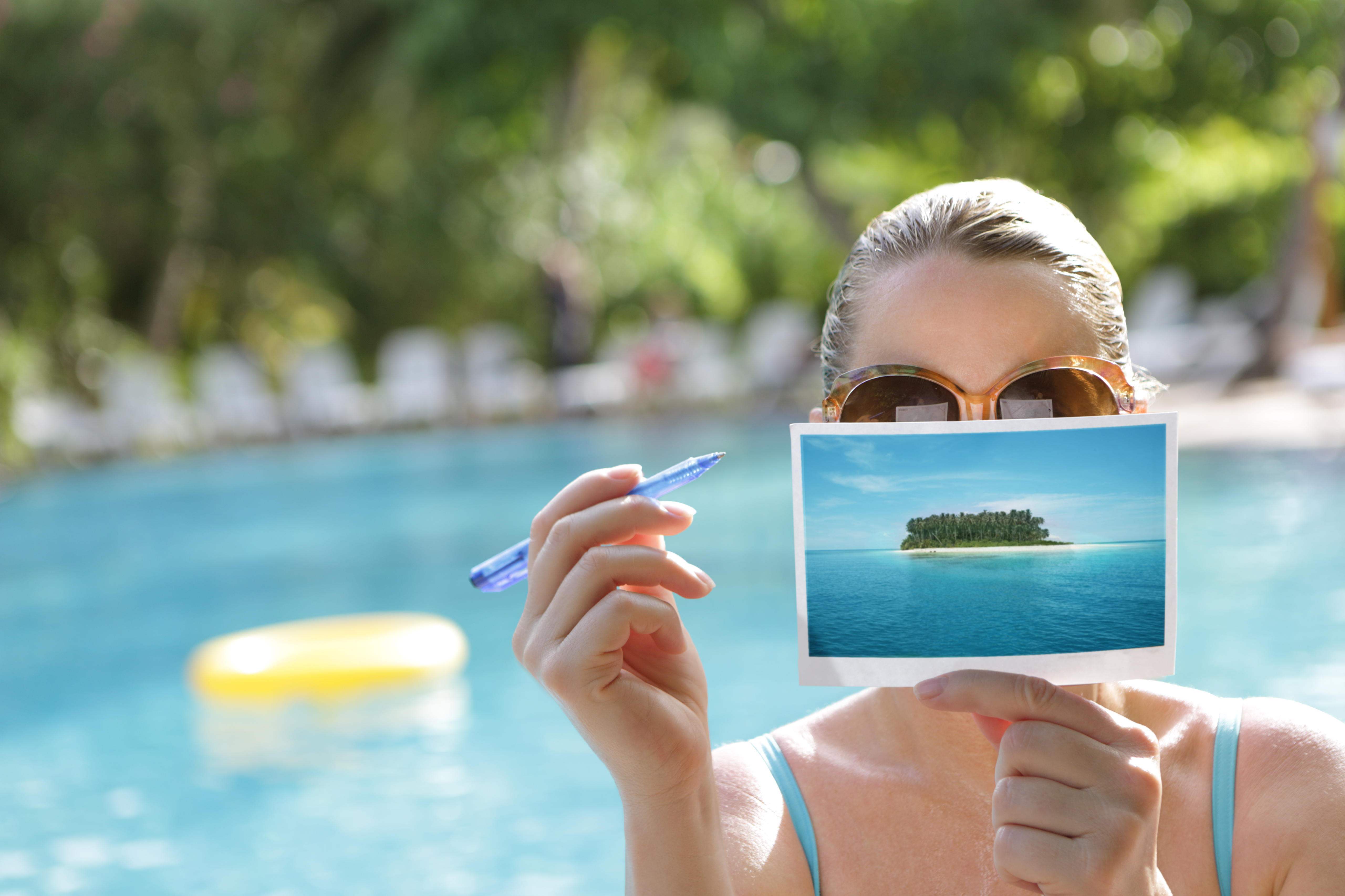 Une femme écrivant une carte postale au bord d'une piscine | Source : Getty Images