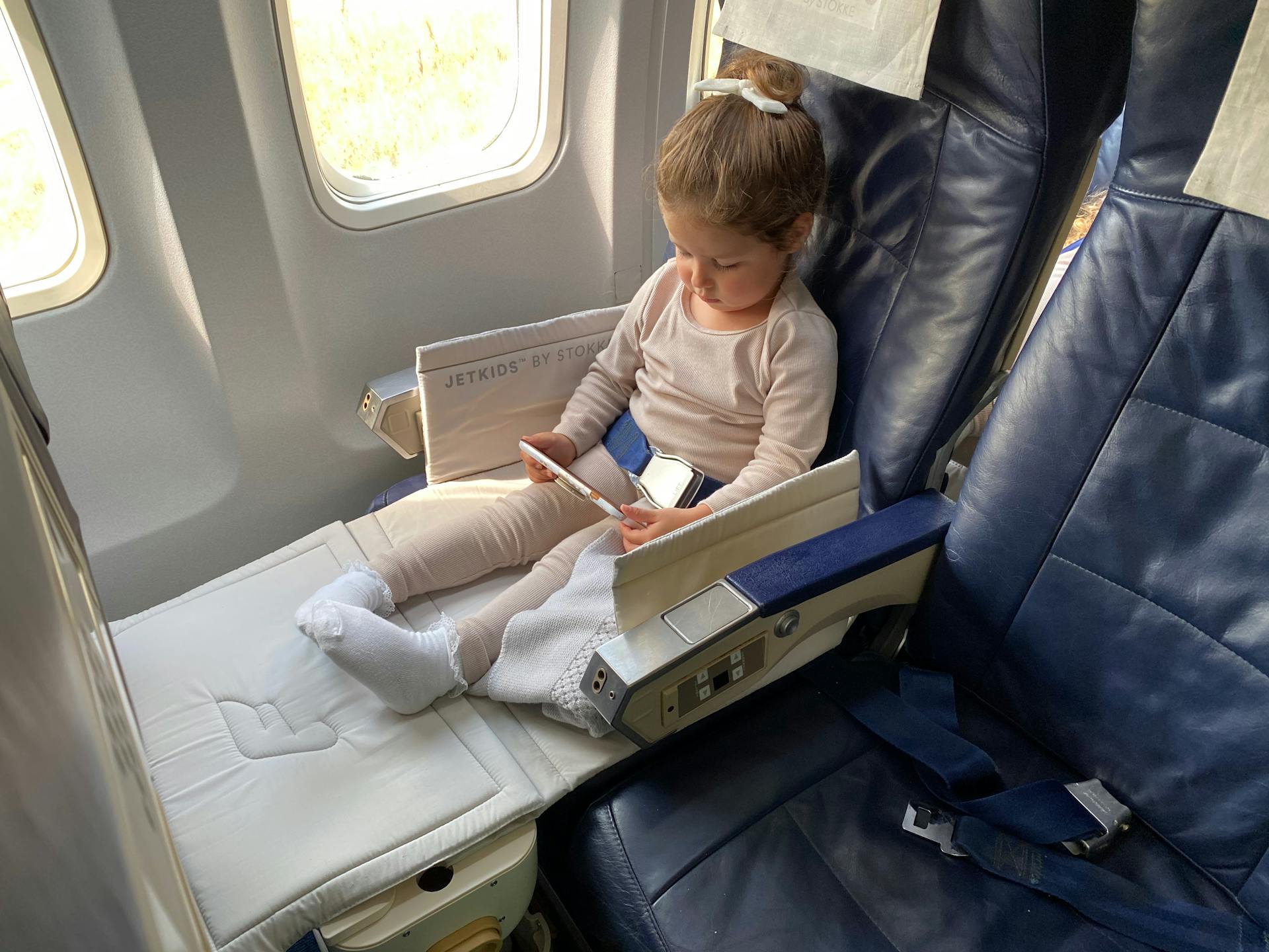 Petite fille tenant une tablette dans un avion | Source : Pexels