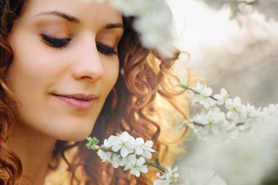 Une femme regarde une fleur | Photo : Pixabay