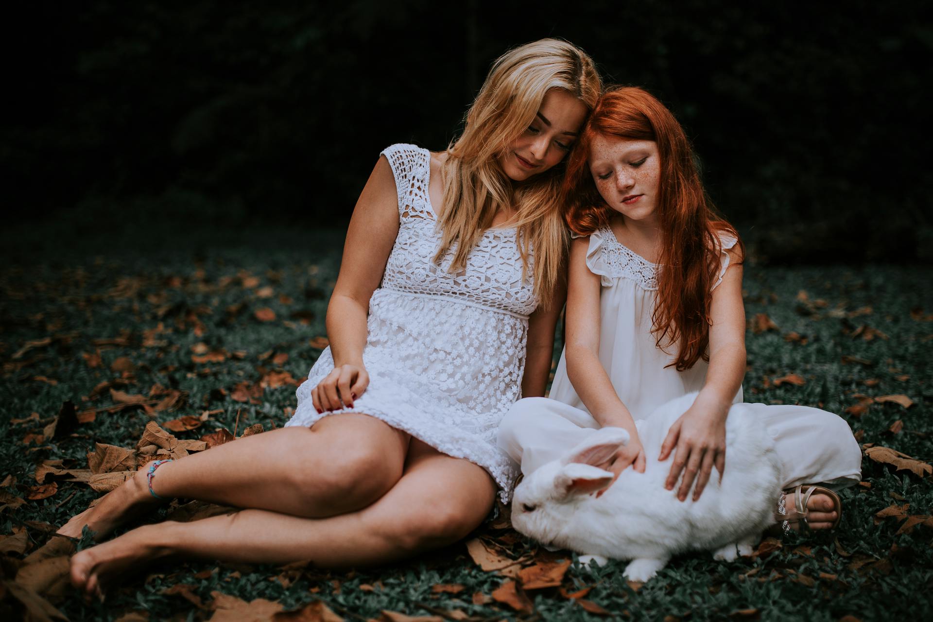 Une femme assise dans l'herbe avec une petite fille | Source : Pexels