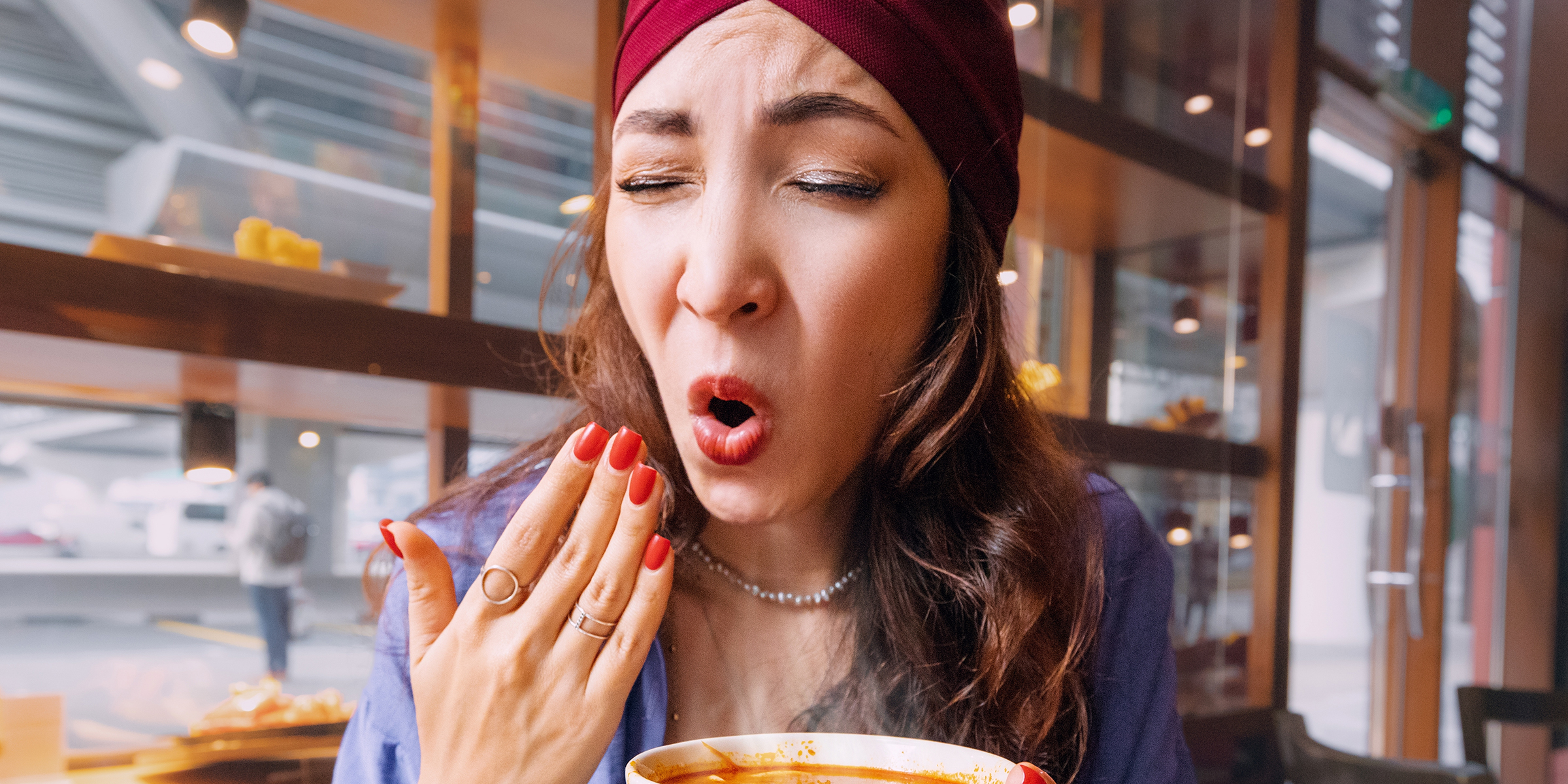 Une femme tirant la tronche et s'éventant au niveau de sa bouche ouverte | Source : Shutterstock