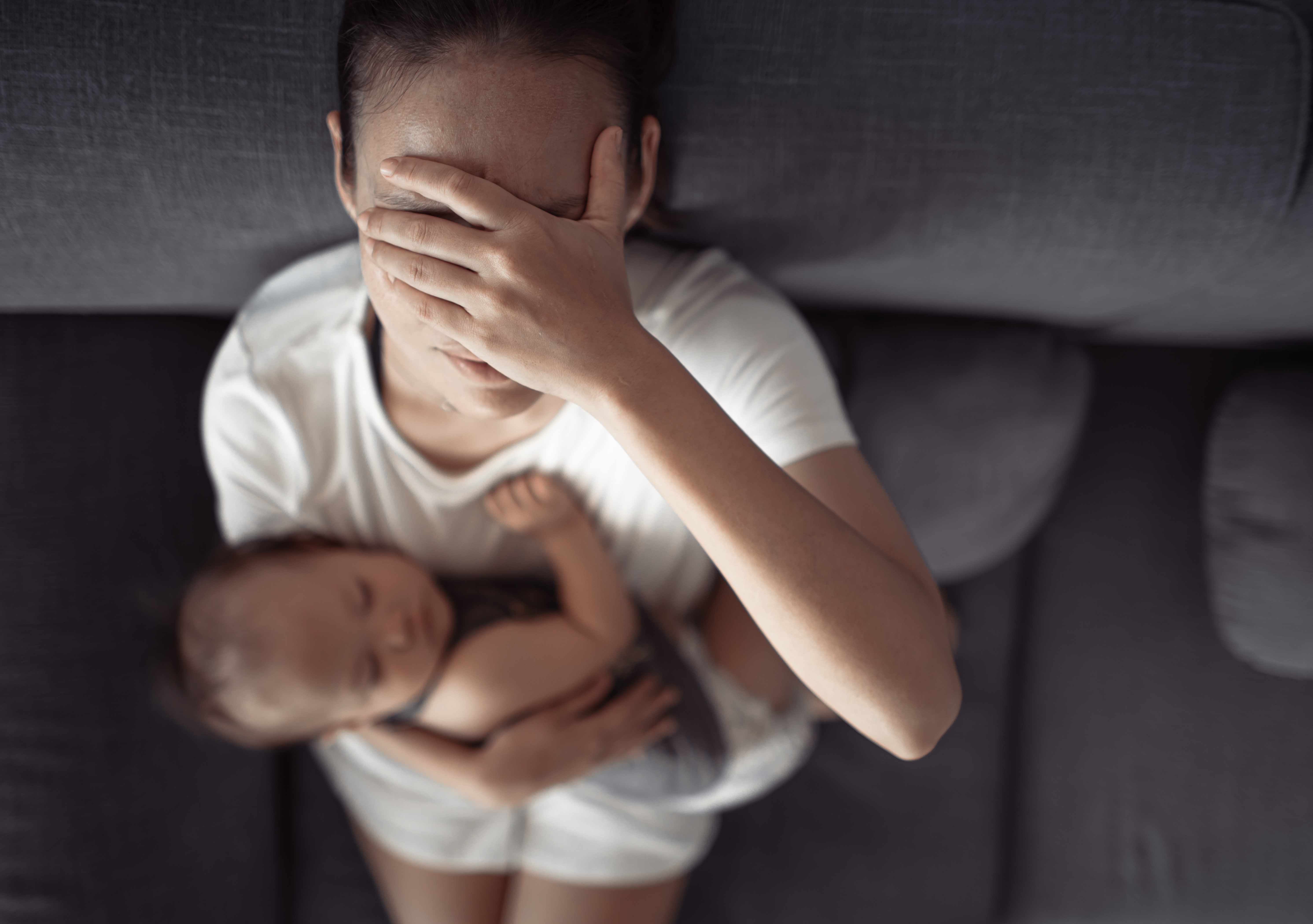 Une femme tenant un bébé tout en se couvrant le visage | Source : Shutterstock