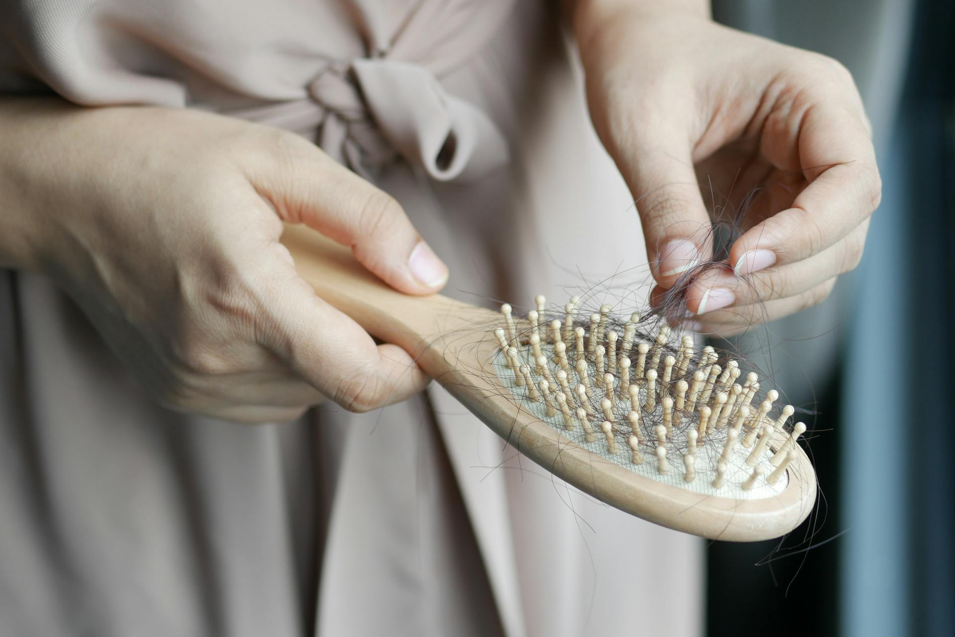 Photo recadrée d'une femme en train d'enlever les cheveux d'une brosse | Source : Pexels