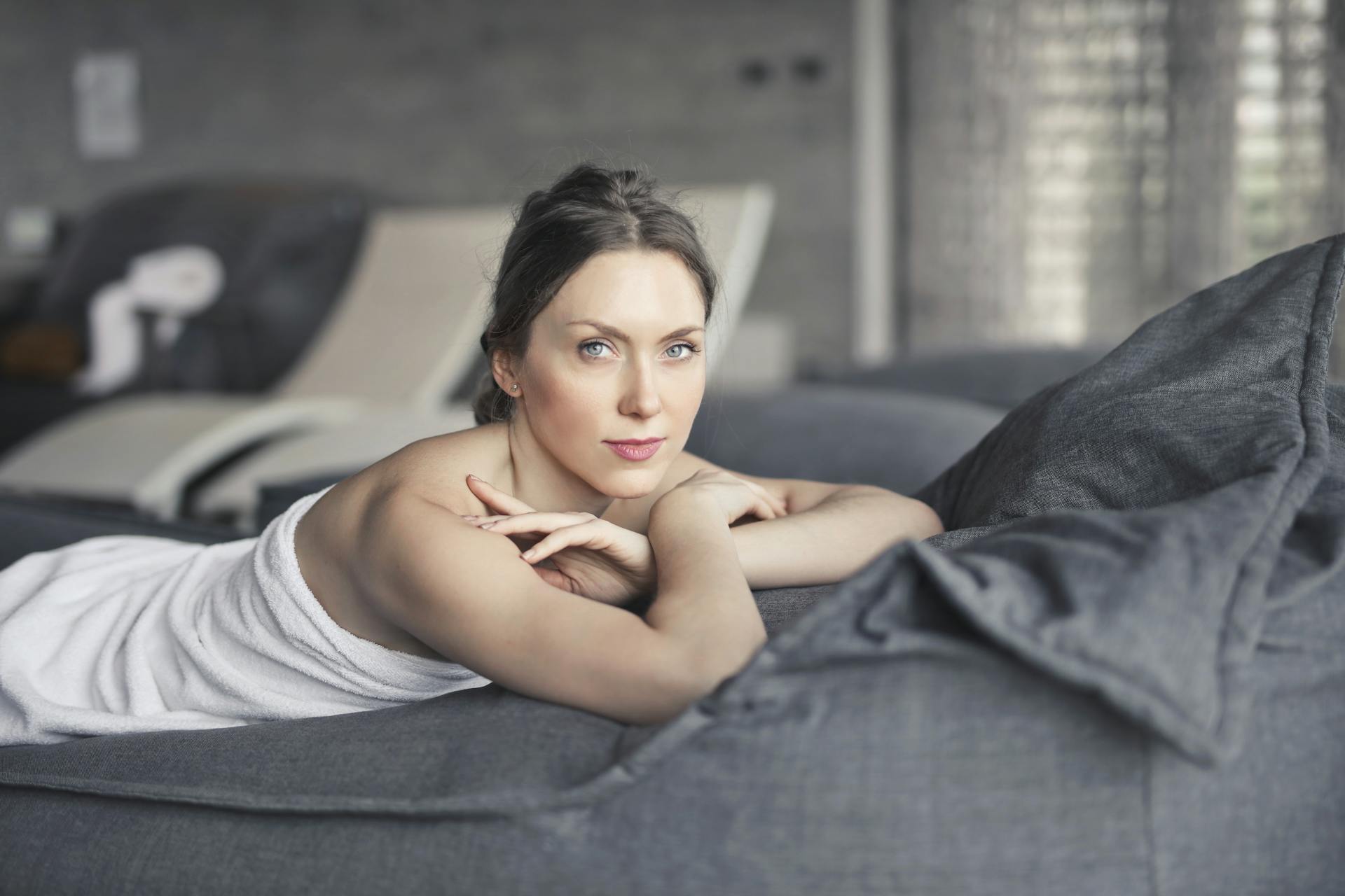 Une femme couverte d'une serviette allongée sur un lit | Source : Pexels
