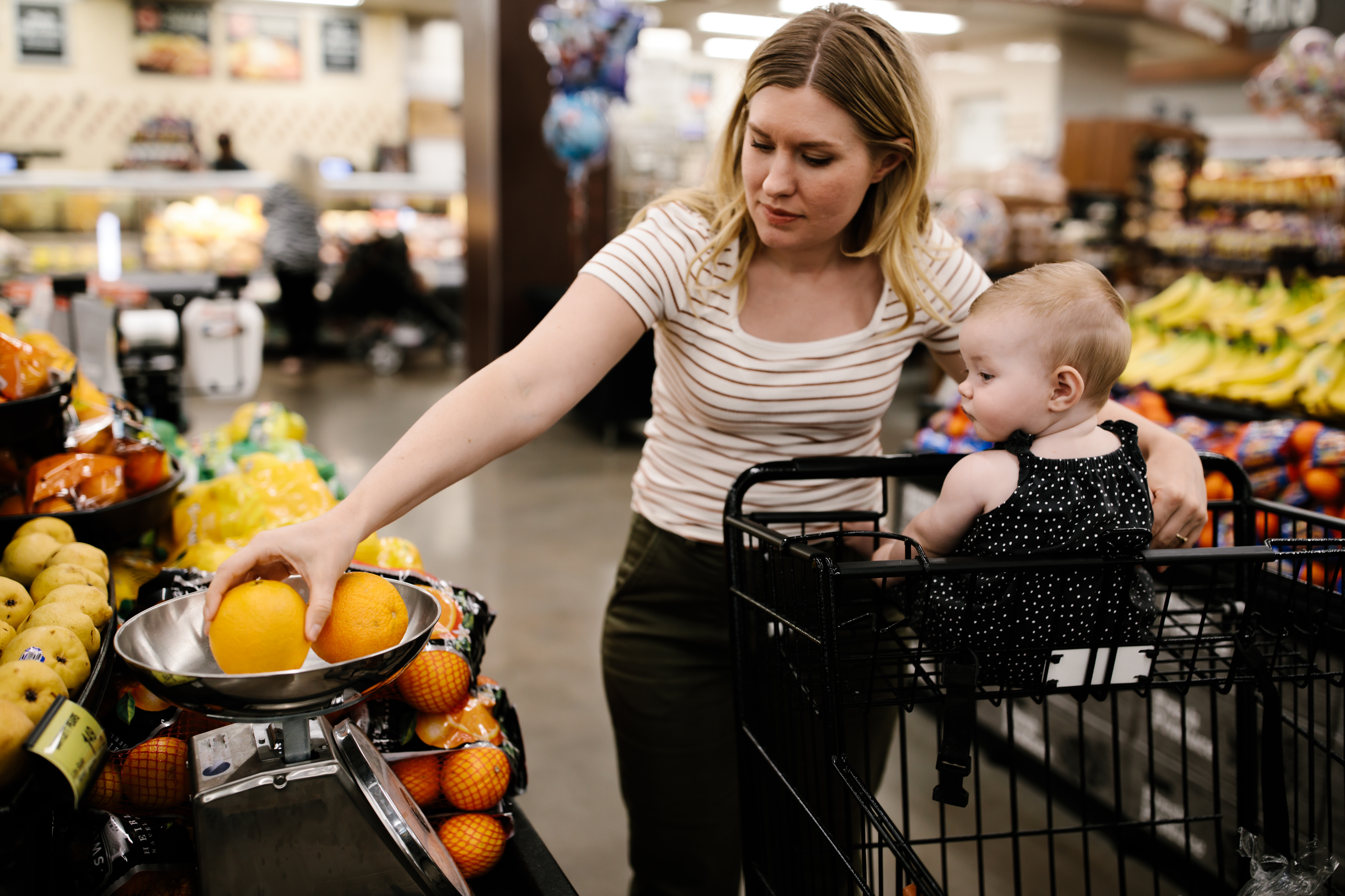 Mère avec sa petite fille achetant des fruits frais à l'épicerie | Source : Getty Images