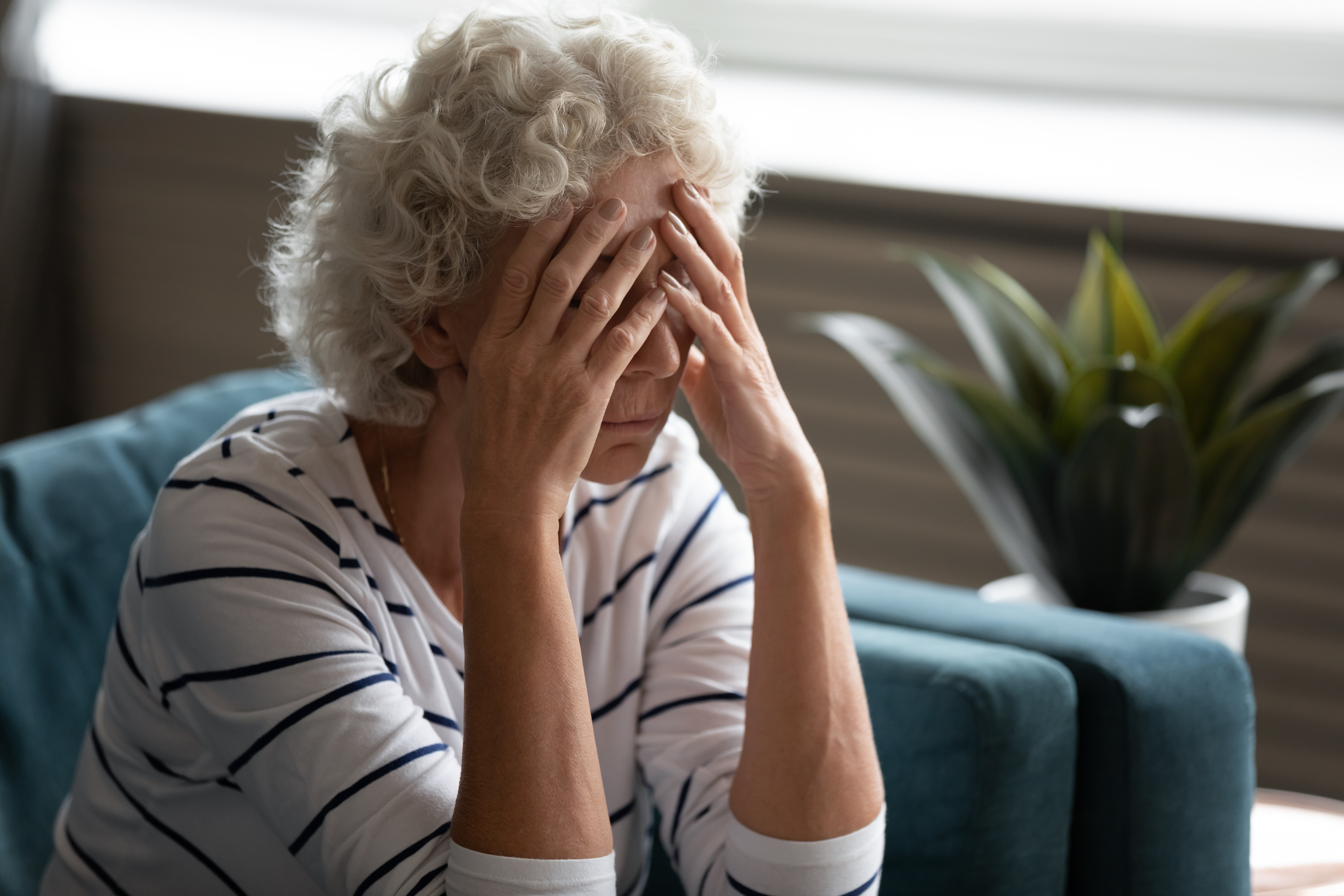 Une femme âgée contrariée se couvrant le visage alors qu'elle est assise | Source : Shutterstock