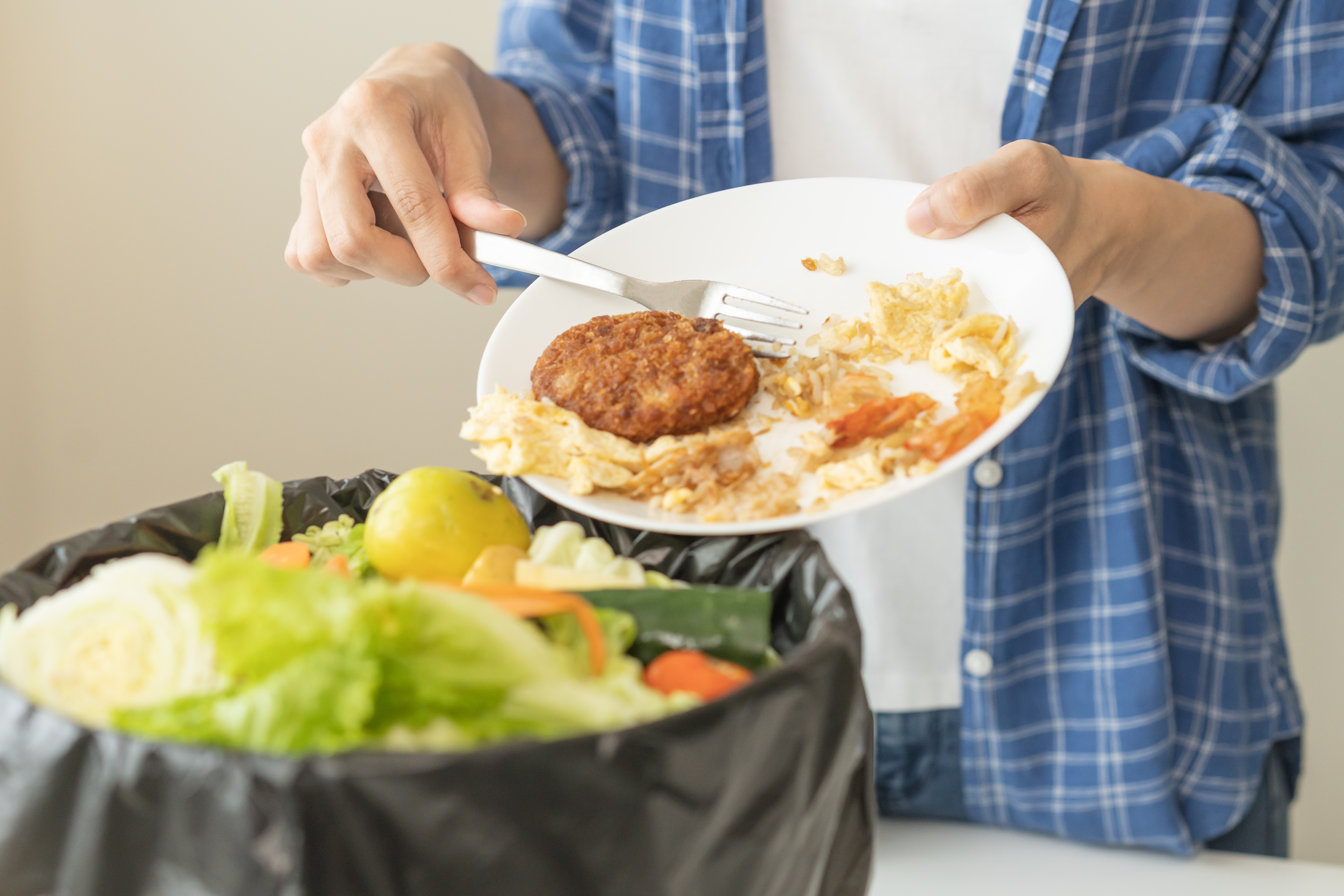 Un homme jetant de la nourriture dans une poubelle | Source : Shutterstock