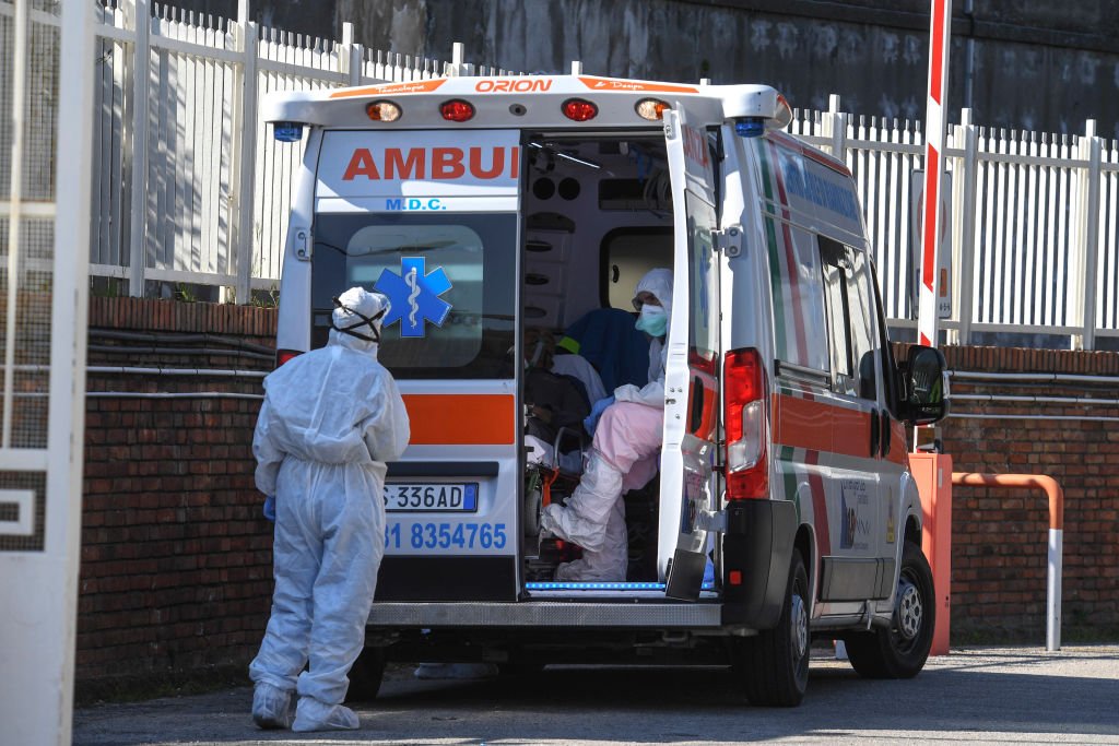 Des ambulanciers paramédicaux ouvrent une ambulance avec un patient Coronavirus COVID-19. | Photo : Getty Images
