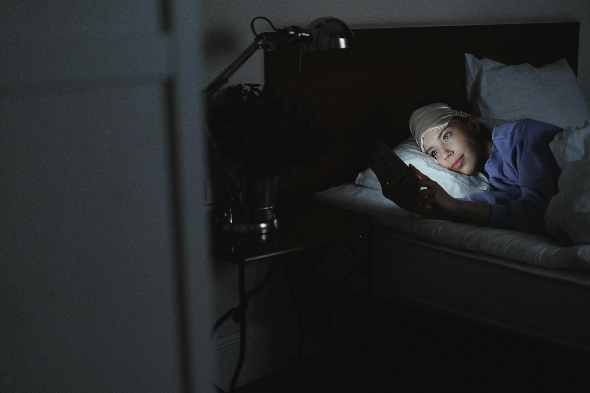 Une femme au lit tenant un téléphone portable | Source : Pexels
