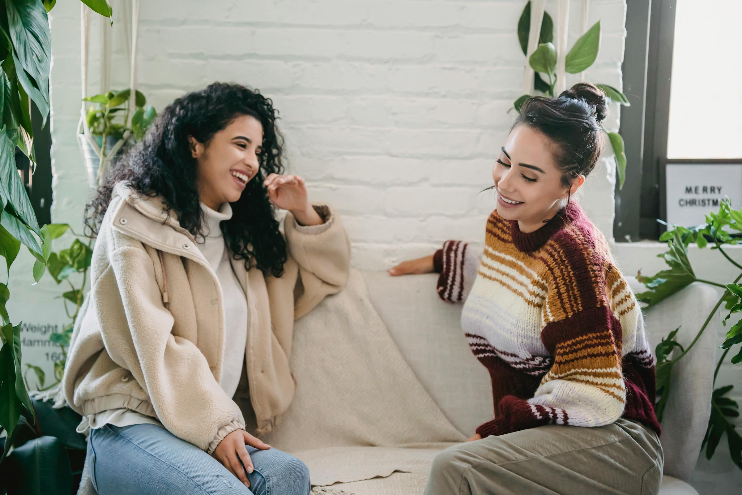 Deux femmes riant sur un canapé | Source : Pexels