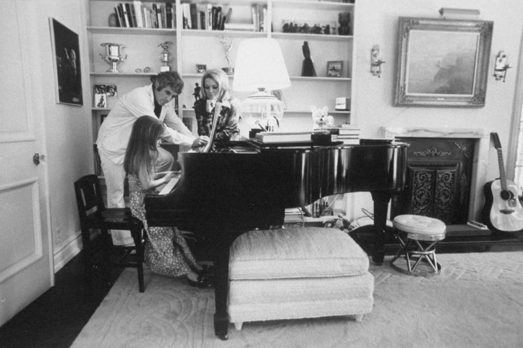 Burt Bacharach et sa femme Angie Dickinson regardant Nikki jouer du piano en mai 1974 | Photo : Getty Images
