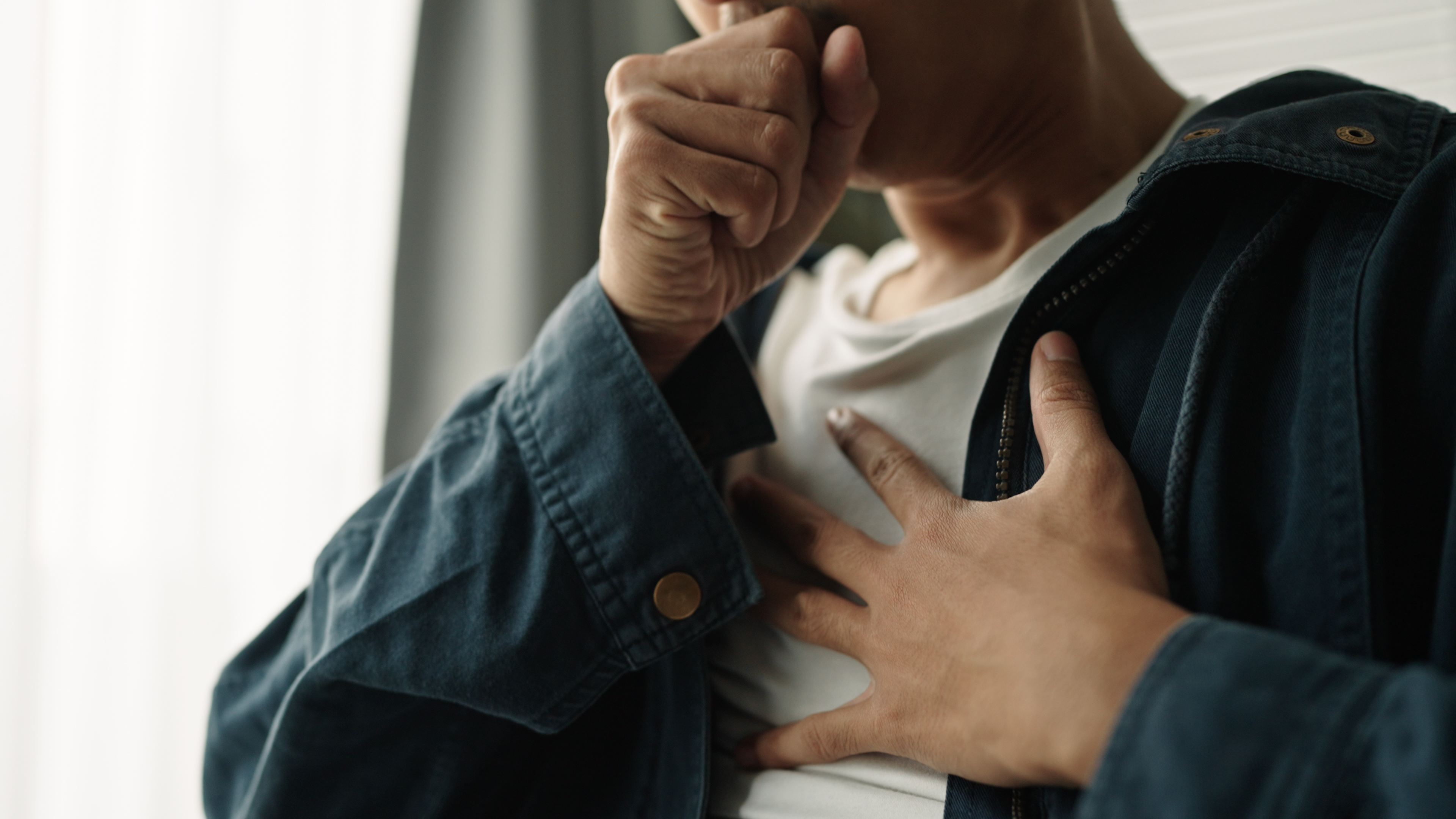 Jeune homme se touchant la poitrine, semblant éprouver de l'inconfort ou de la douleur | Source : Getty Images