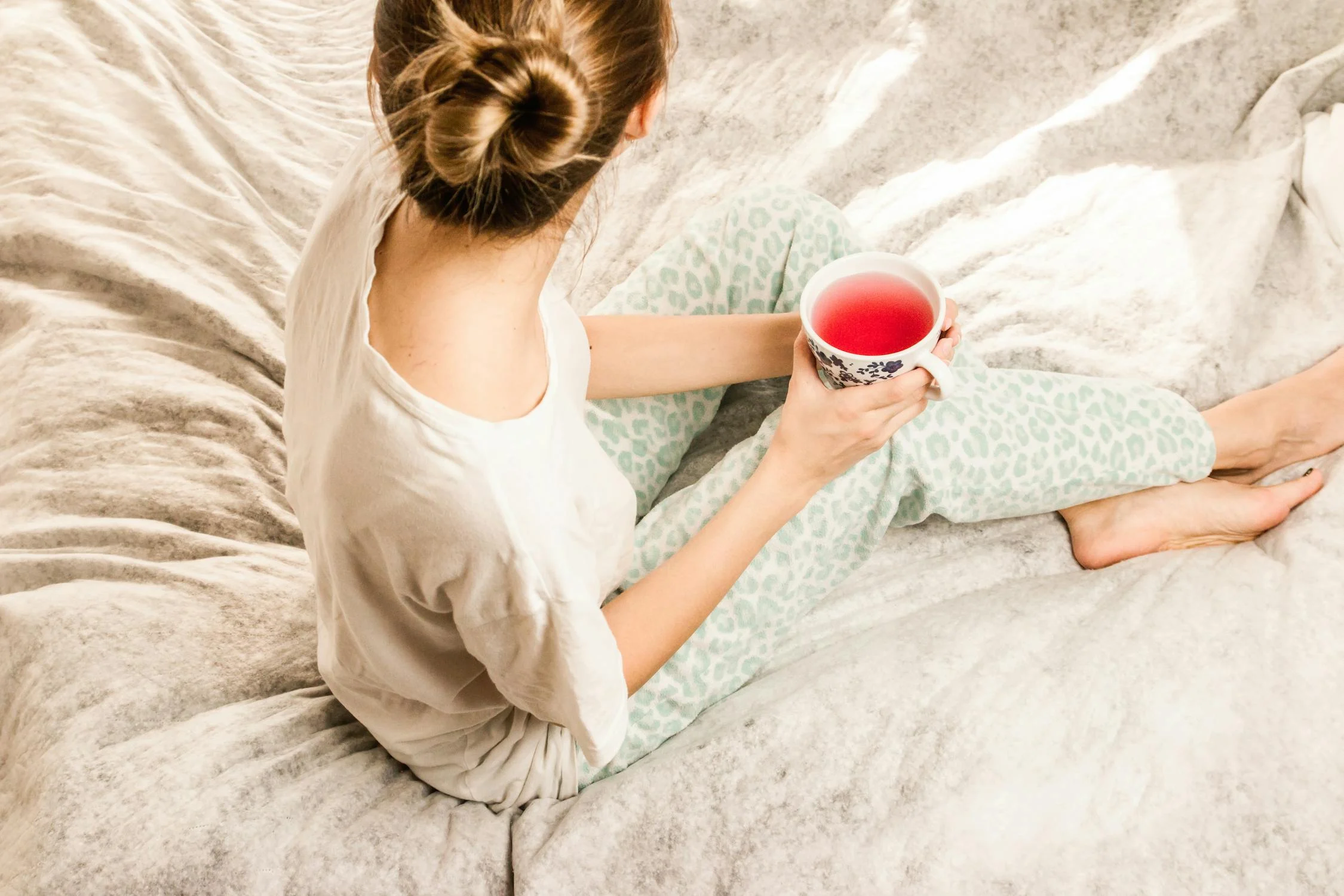 A woman drinking tea in her bed ⏐ Source: Pexels