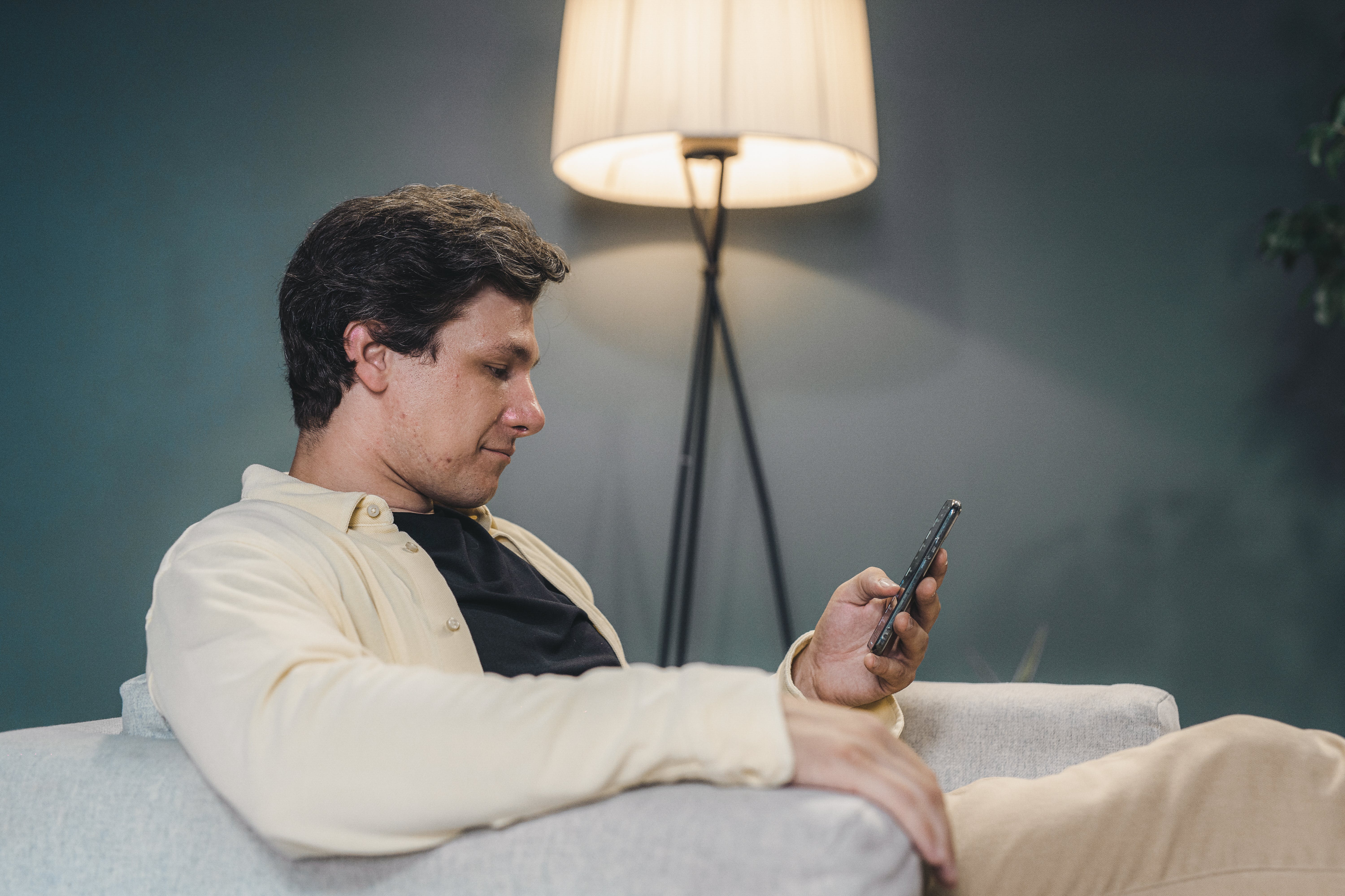 Un homme assis sur un canapé utilisant un smartphone | Source : Pexels