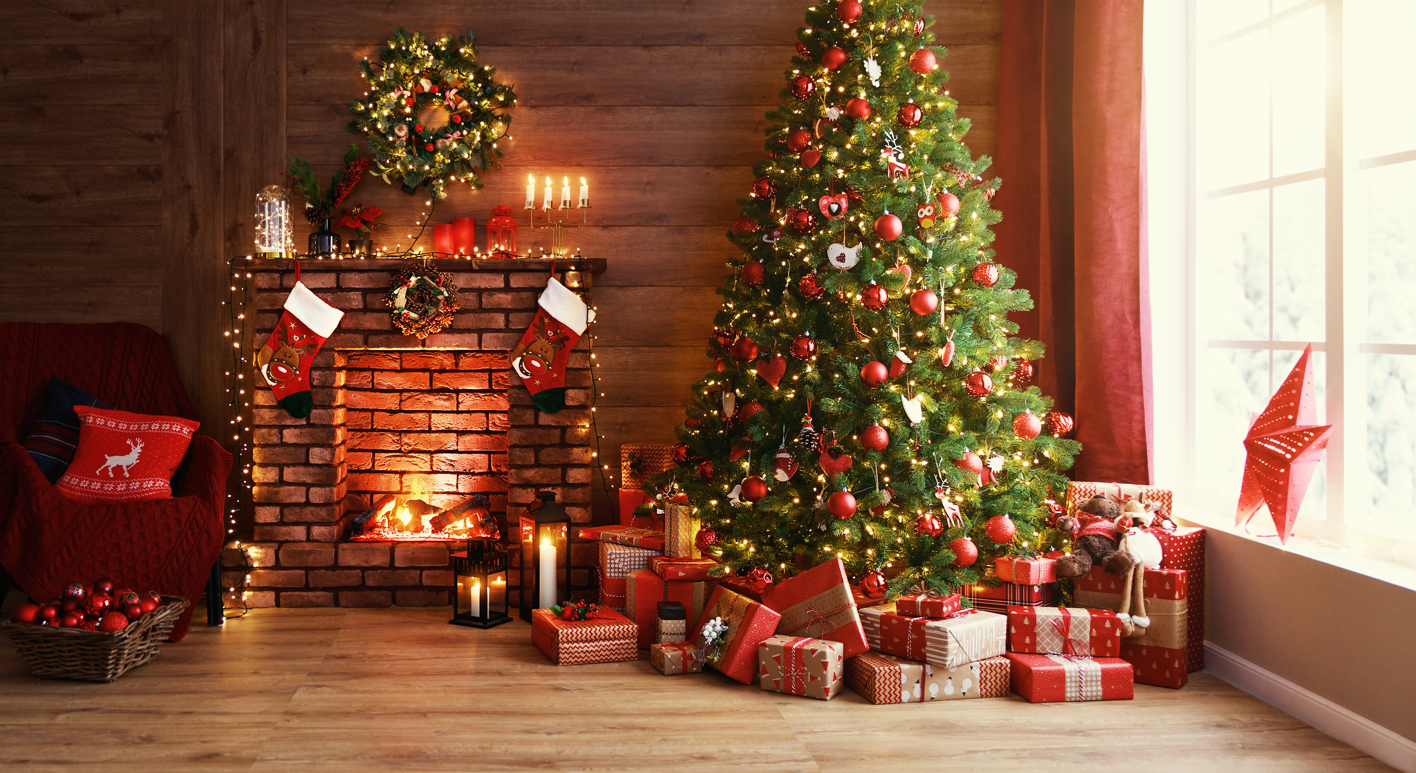 Un sapin de Noël placé près d'une cheminée avec des cadeaux et des décorations | Source : Shutterstock