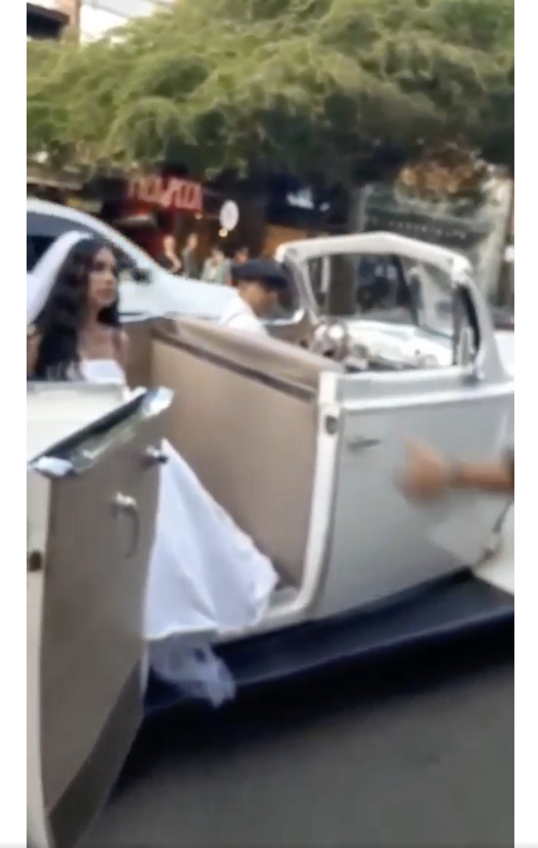 Une femme vêtue d'une robe de mariée blanche est photographiée dans un véhicule de mariage classique sur la route. | Source : facebook.com/maspopulareventos