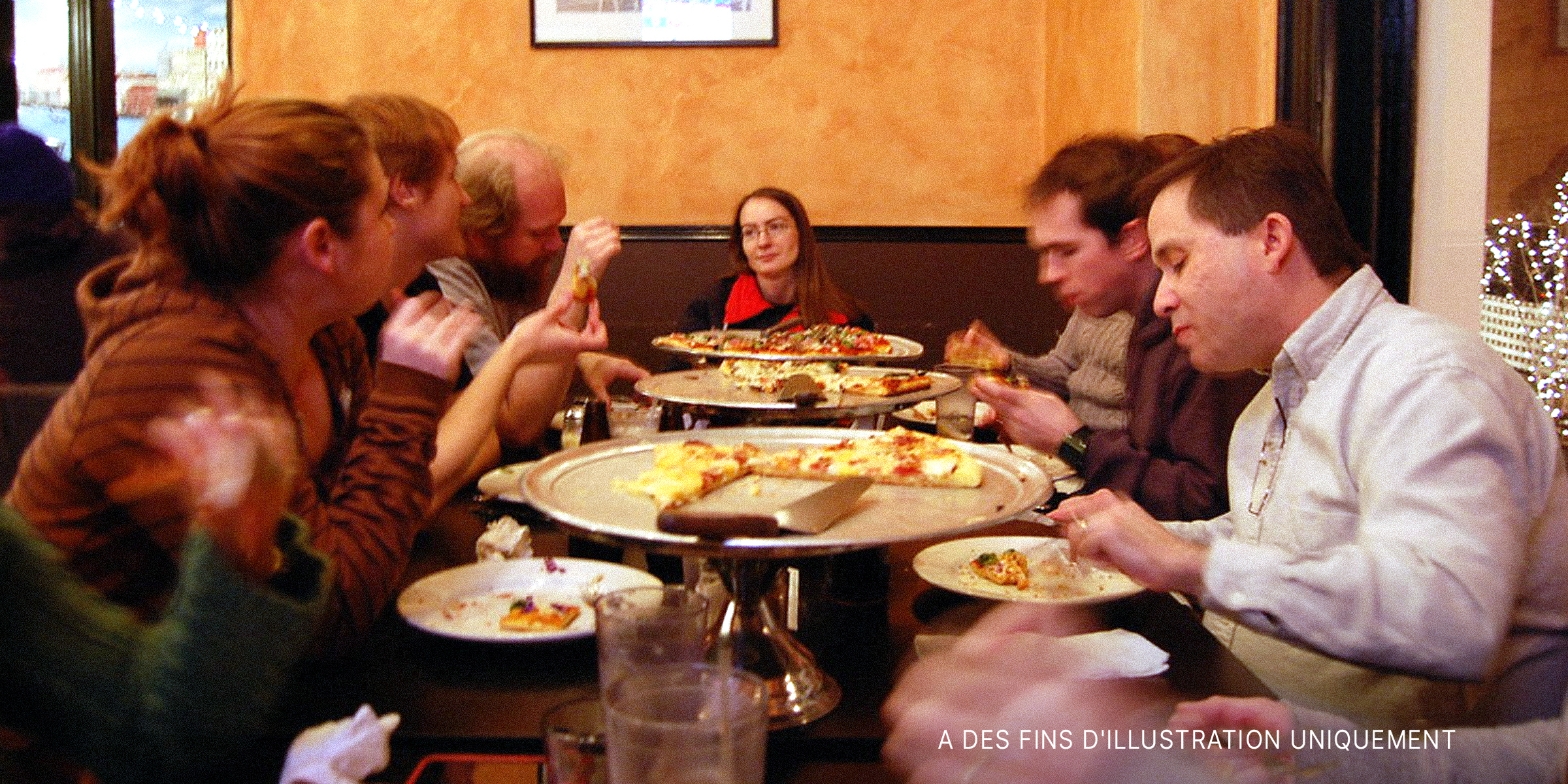 Des gens assis autour d'une table et mangeant | Source : Flickr
