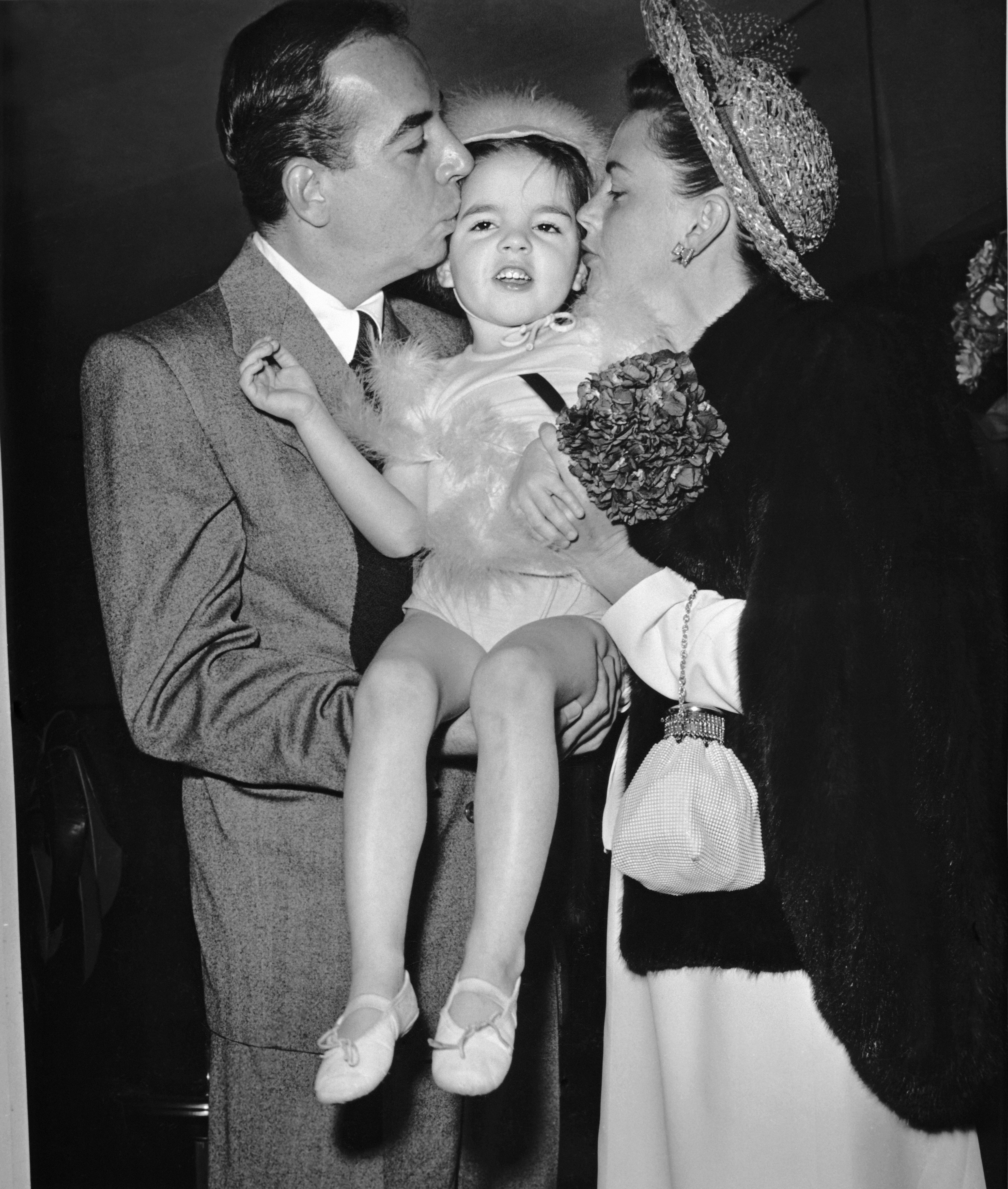 Liza Minnelli reçoit des baisers de sa mère, Judy Garland, et de son père, Vincente Minnelli, en avril 1947 à Hollywood, en Californie. | Source : Getty Images
