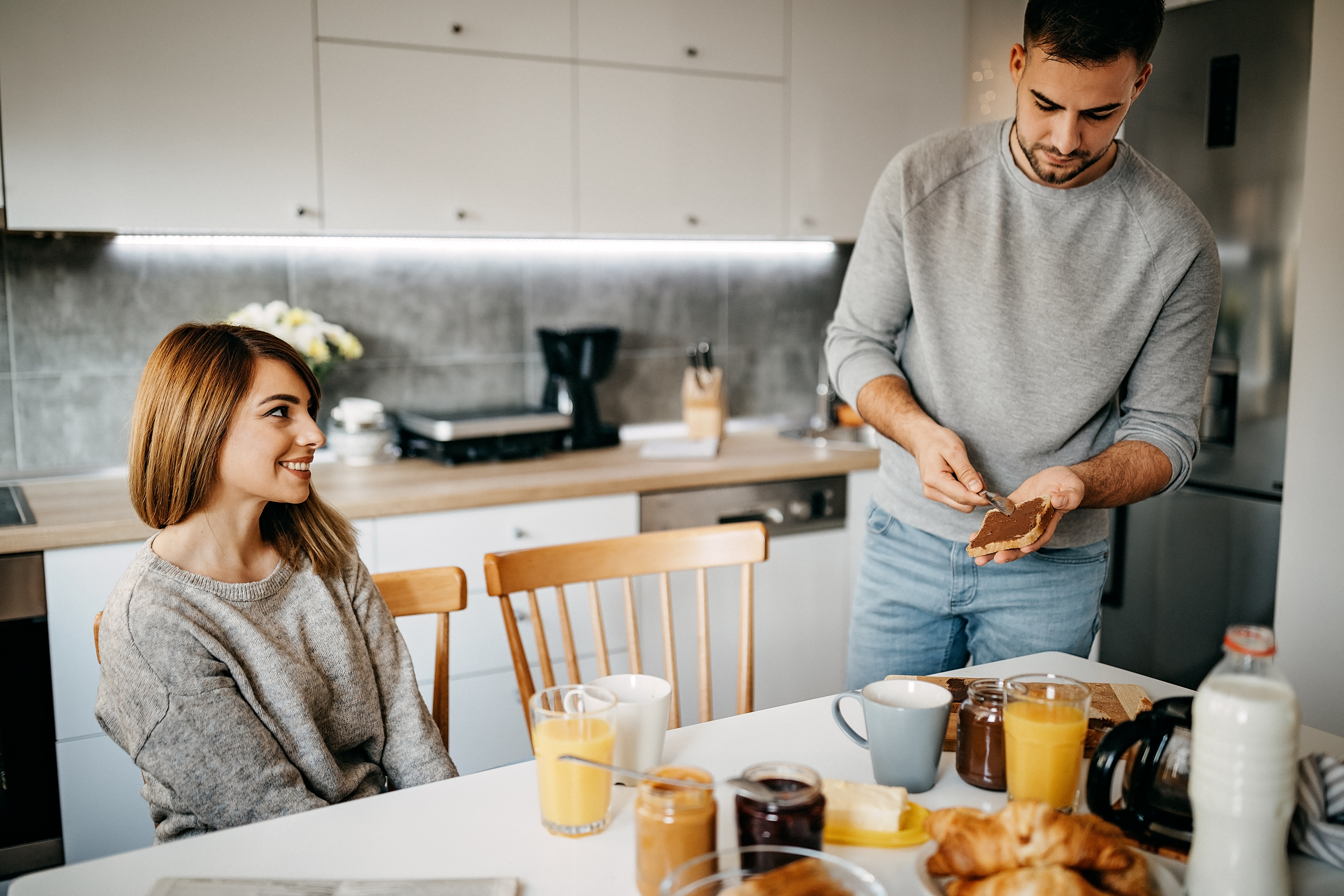 Couple en train de préparer le petit déjeuner dans la cuisine, plein d'émotions | Source : Getty Images