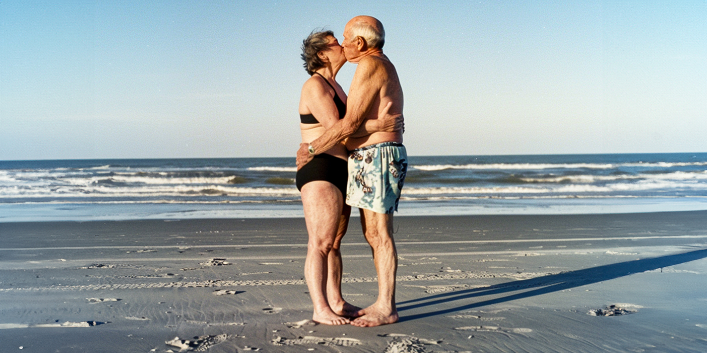 Un couple de personnes âgées s'embrasse sur la plage | Source : AmoMama