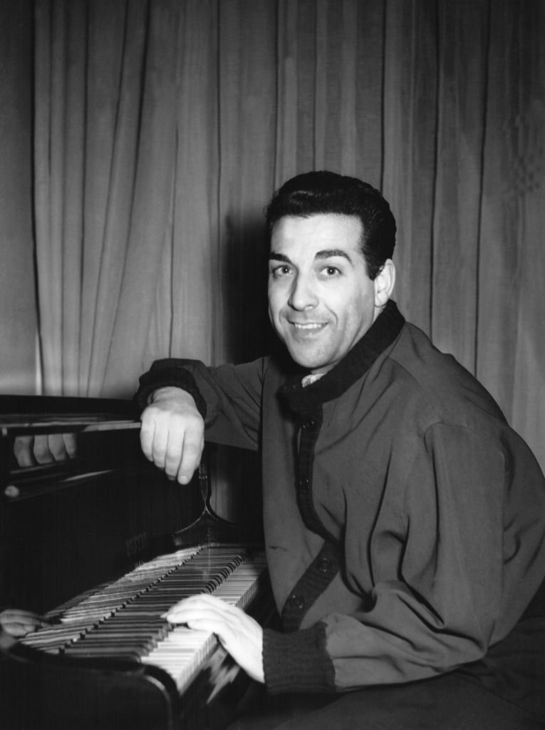 Le chanteur espagnol Luis Mariano posant devant un piano, en 1956. | Photo : Getty Images