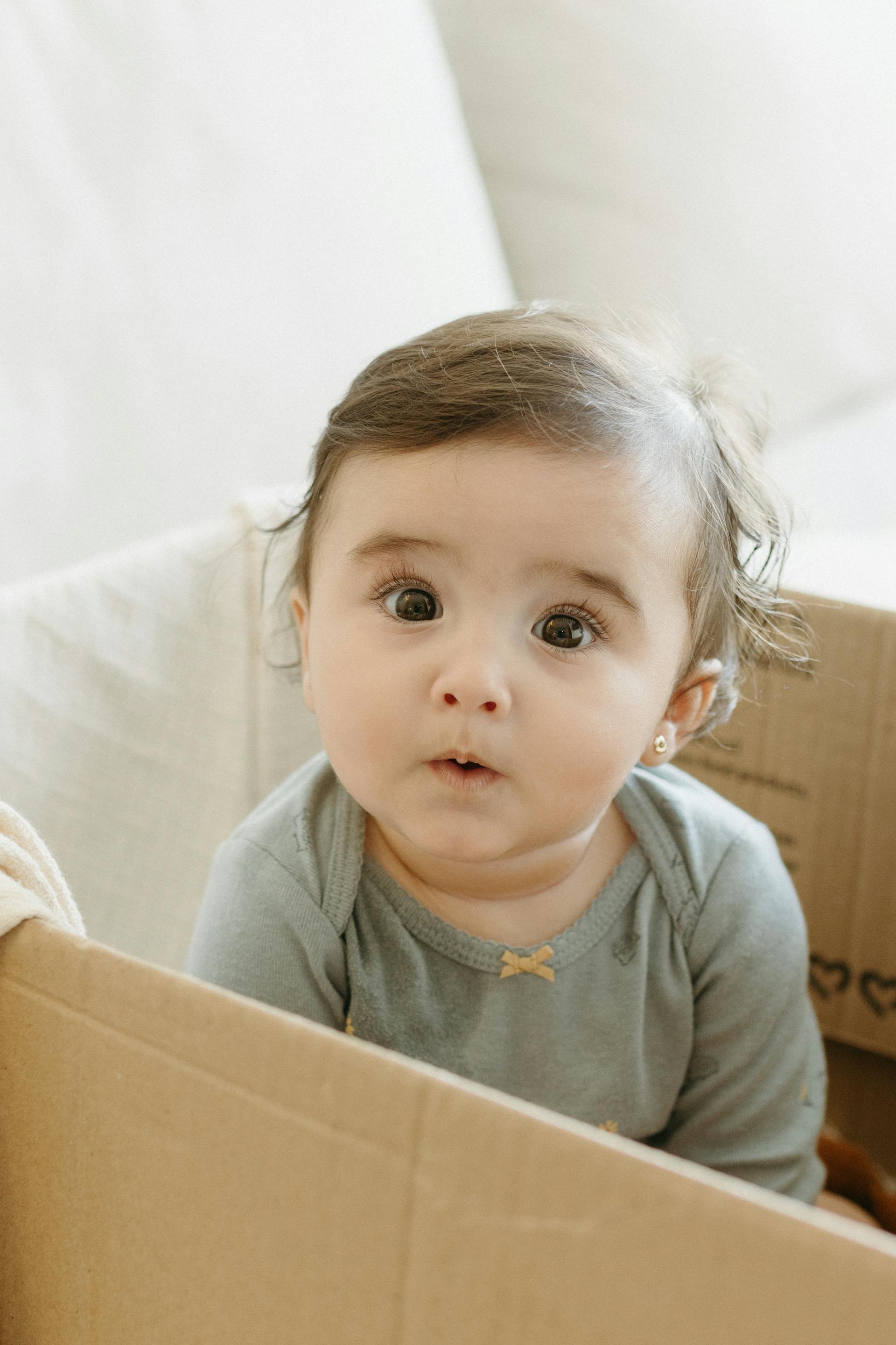 Une petite fille assise dans une boîte | Source : Pexels