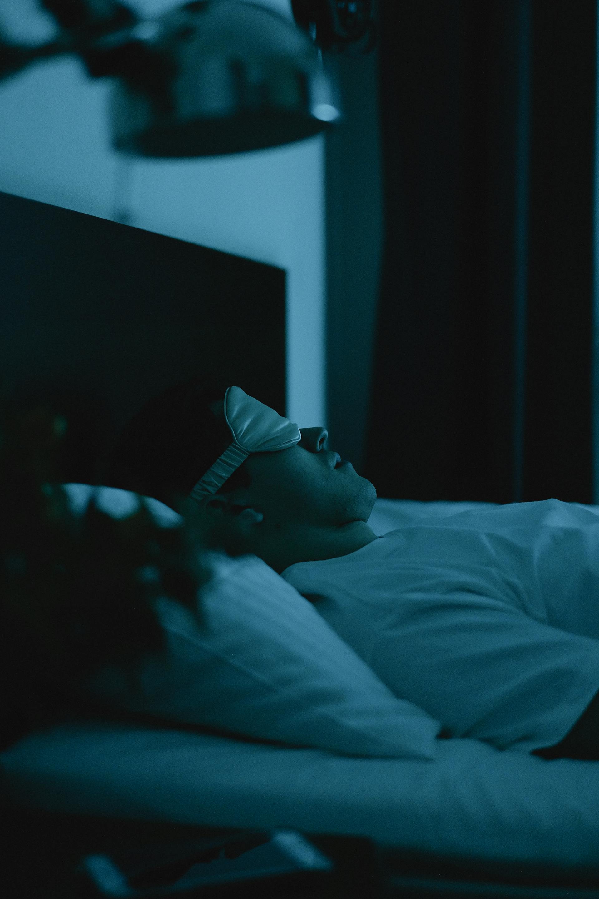 Un homme portant un masque de sommeil alors qu'il est allongé dans son lit | Source : Pexels