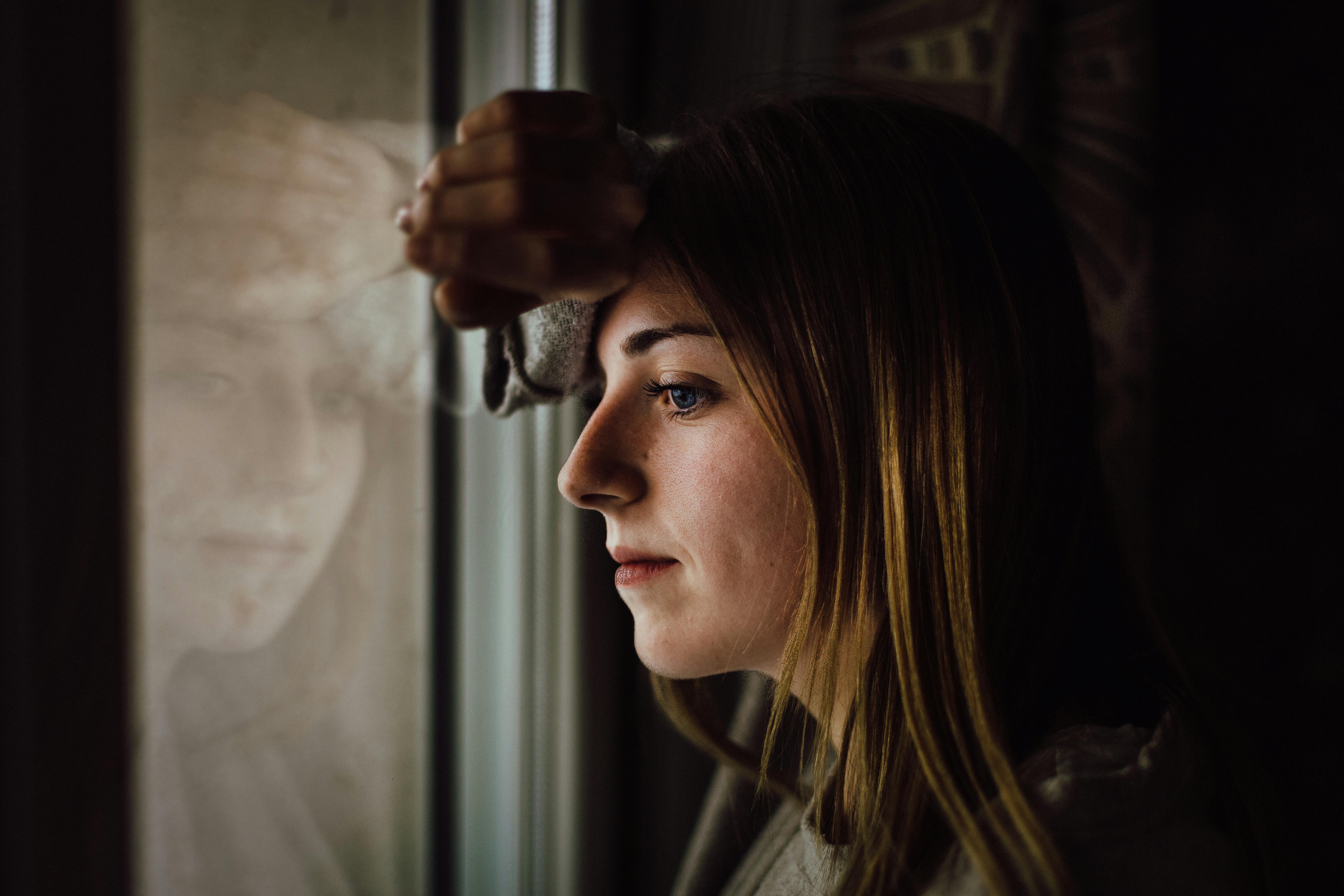 Une femme regardant par la fenêtre et perdue dans ses pensées | Source : Pexels