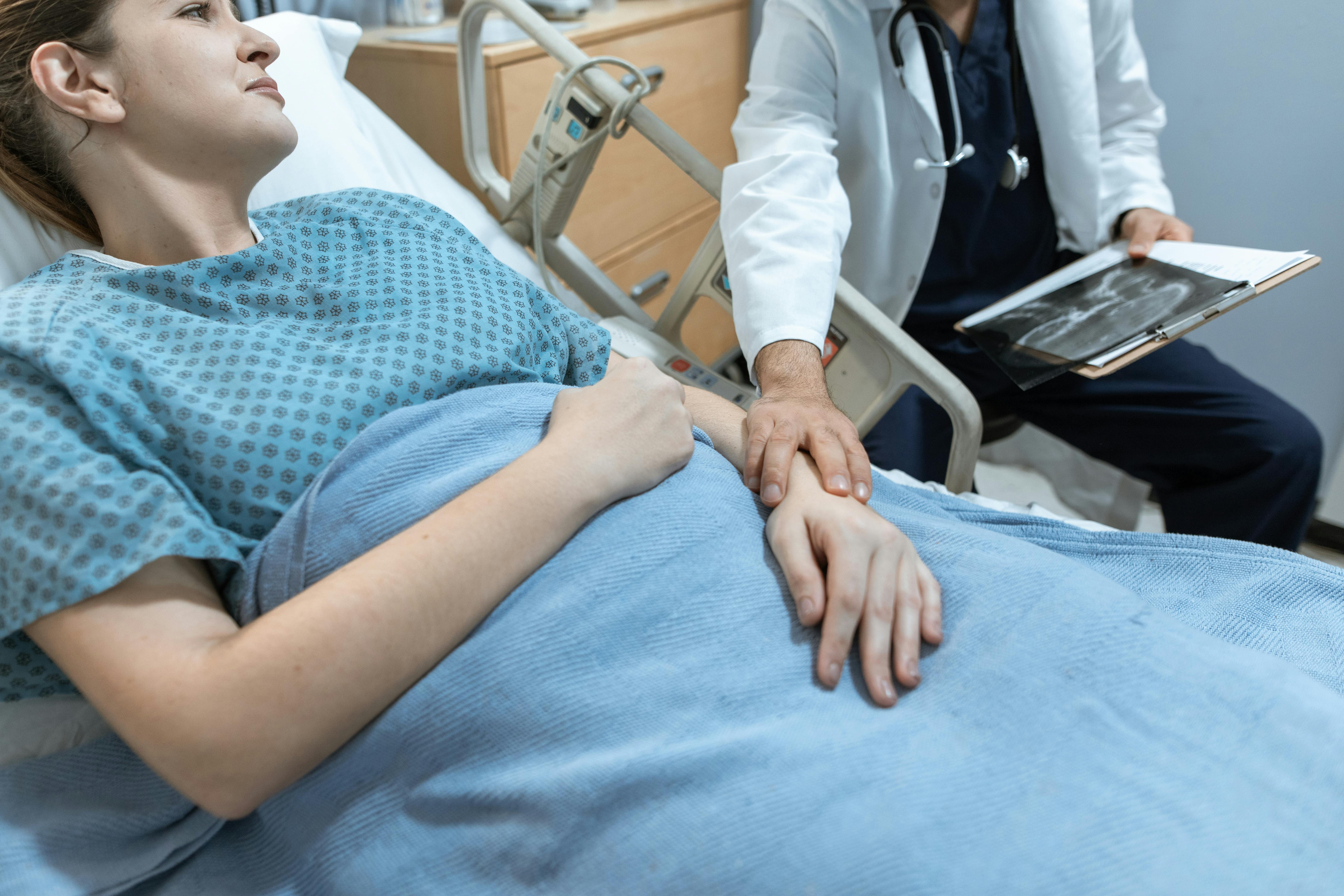 Une femme réconfortée par un médecin alors qu'elle est allongée dans un lit d'hôpital | Source : Pexels