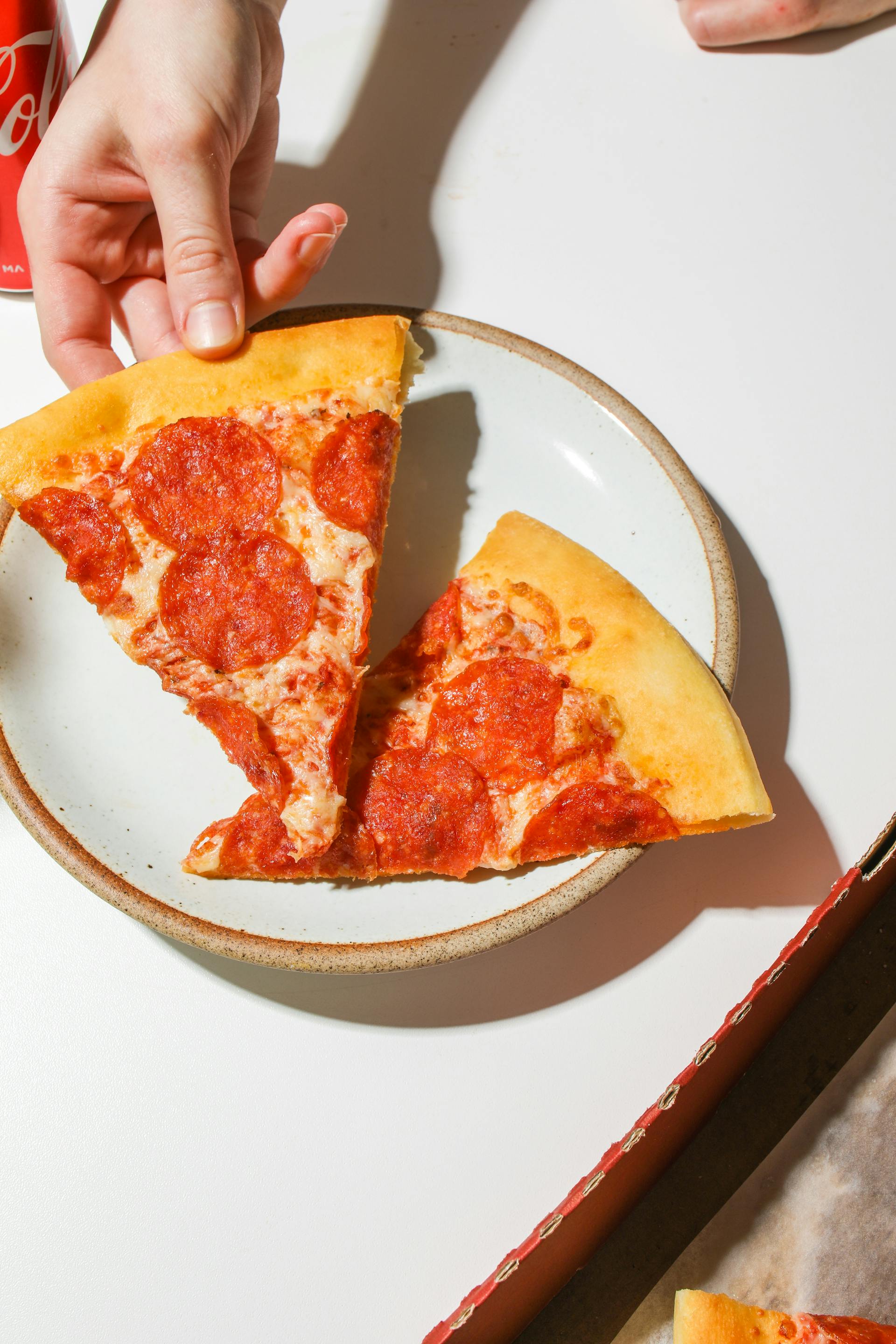 Quelqu'un prend une part de pizza dans une assiette | Source : Pexels