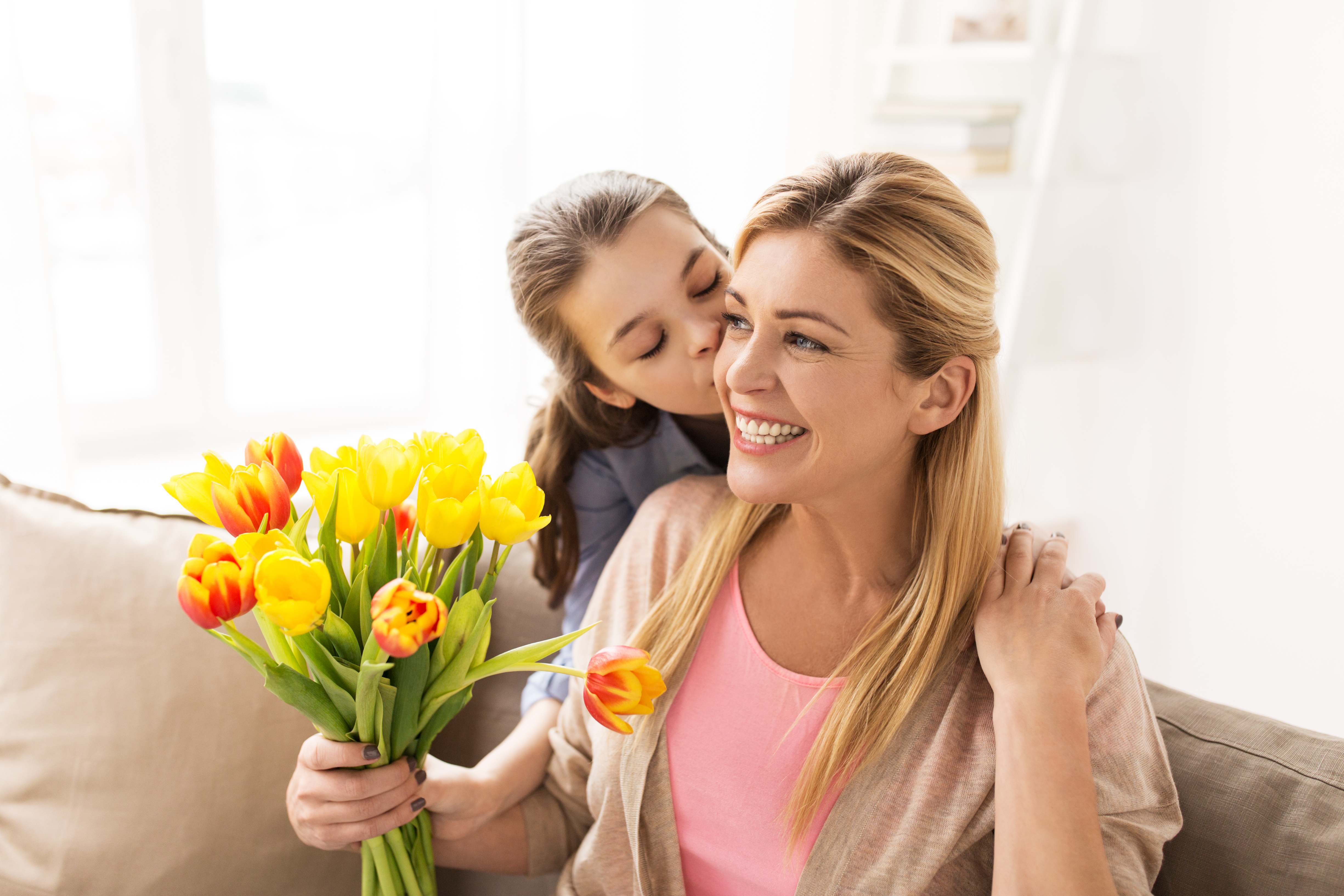 Une adolescente embrasse sa mère et lui offre des fleurs | Source : Shutterstock