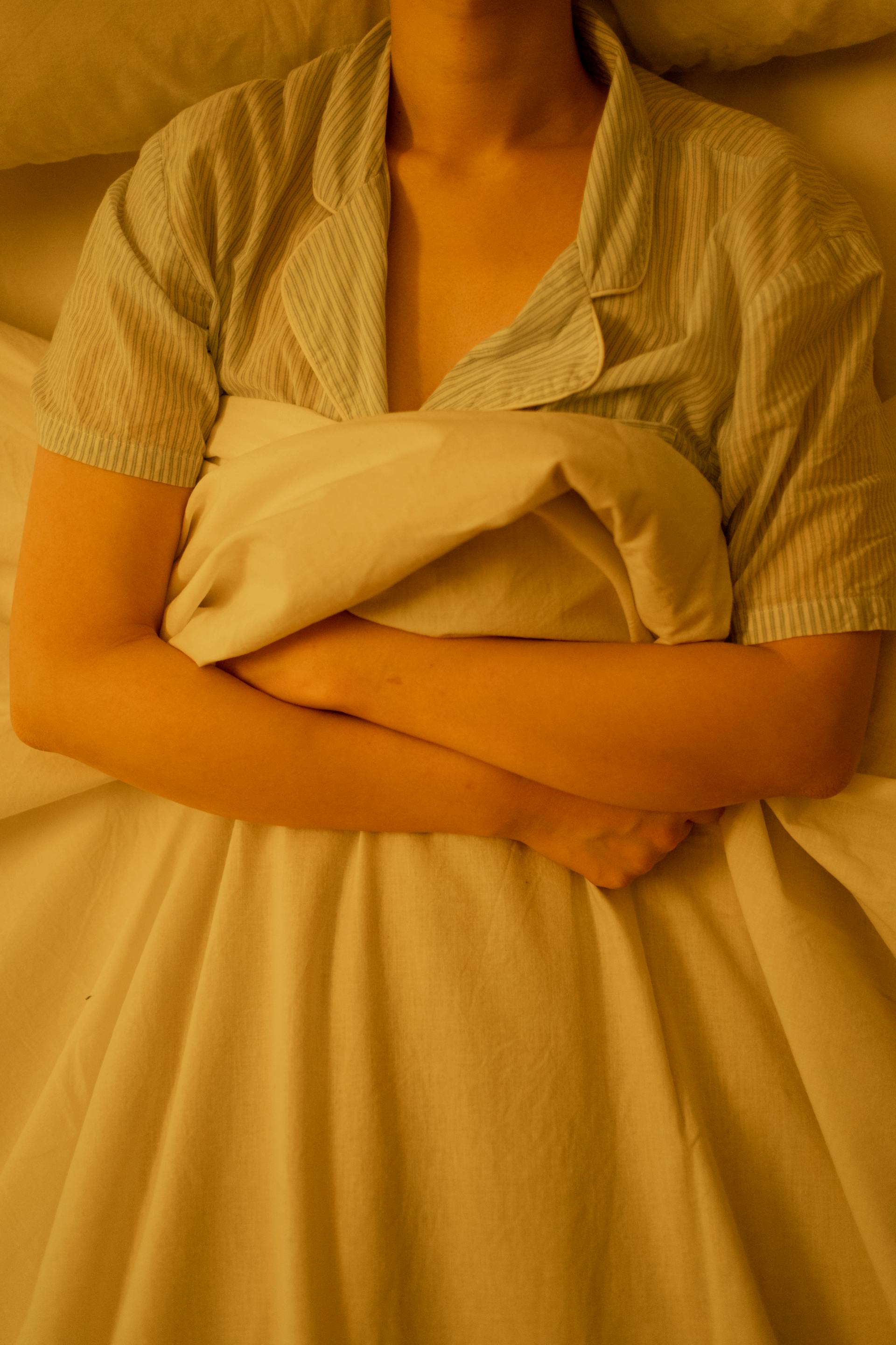Une femme allongée dans son lit saisissant une couverture | Source : Pexels
