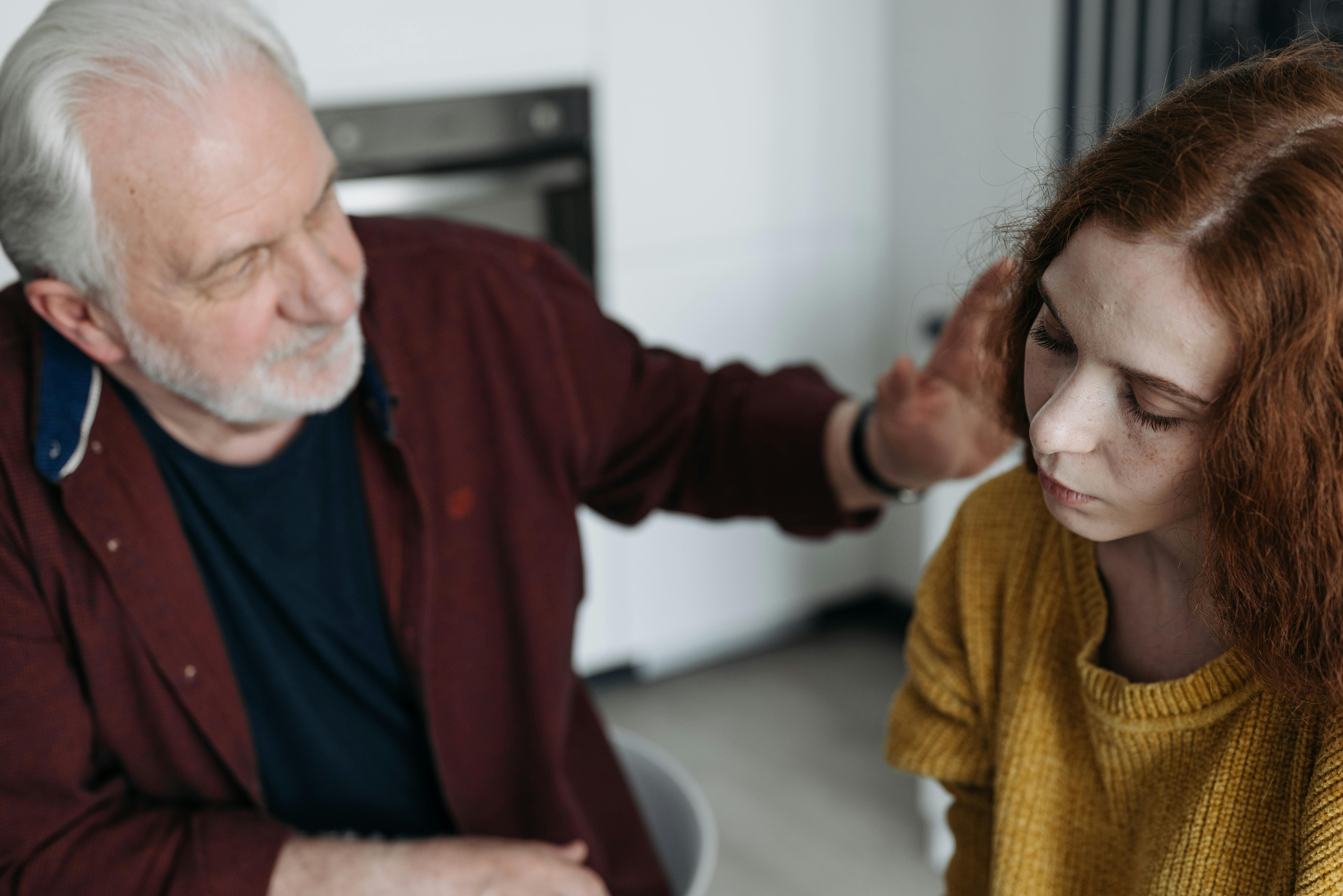 Un homme plus âgé réconforte une jeune fille triste | Source : Pexels